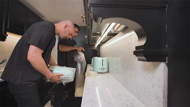 Professional movers carefully packing and organizing boxes inside a modern home, showcasing expert packing and unpacking services during a residential move.