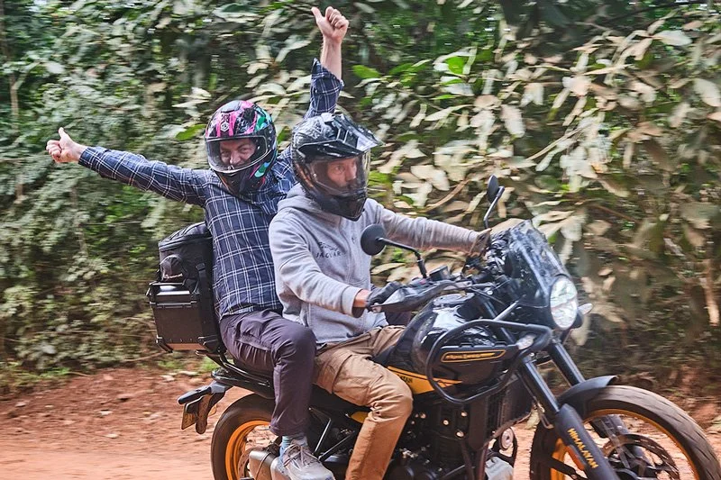 Riders 2 up on a black motorbike enjoying a ride in the Cambodian countryside