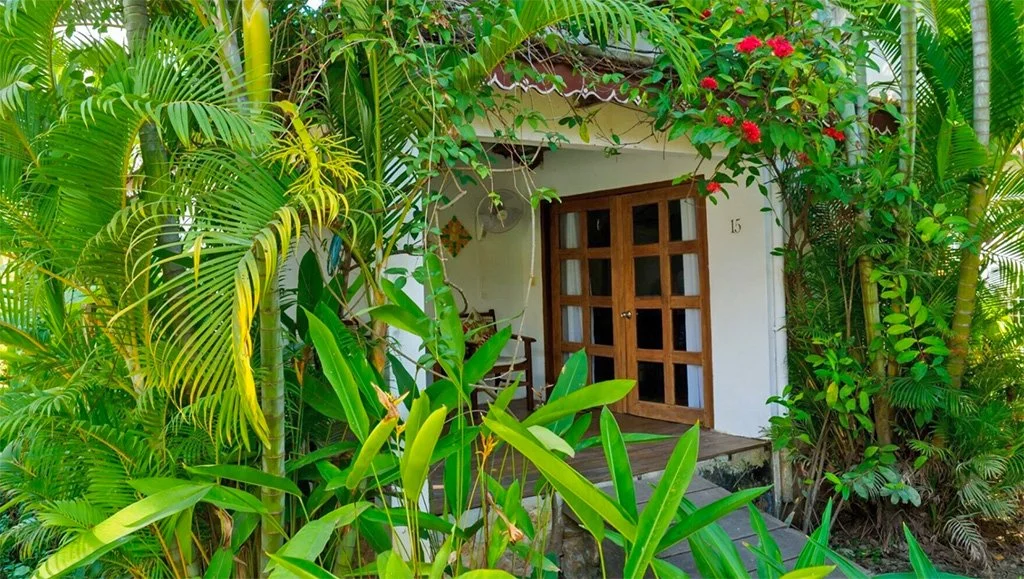 Image of the entrance of a bungalow in a green jungle garden
