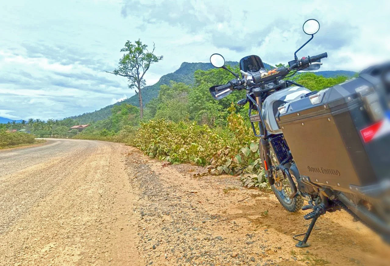 Royal Enfield Himalayan 411 motorbike on the side of a gravel road in the Cambodian Cardamom mountains.