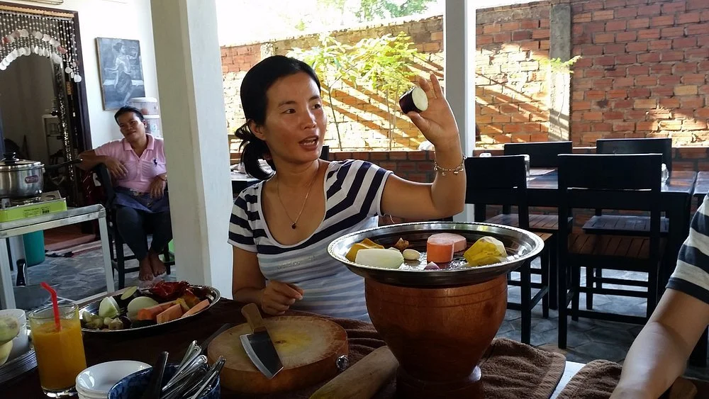 A Cambodian lady showing ingredients in a local cooking class