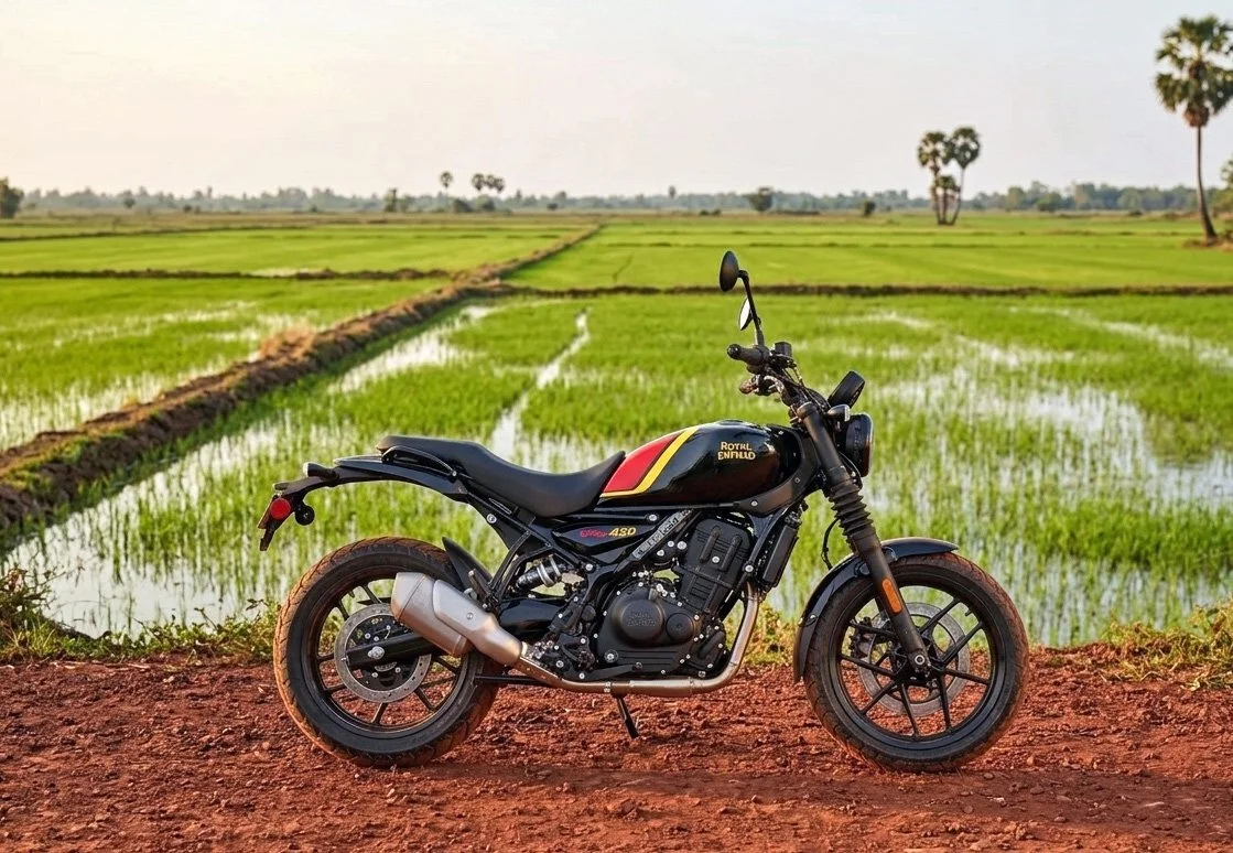 Black Royal Enfield motorbike in front of a rice field and Cambodian landscape