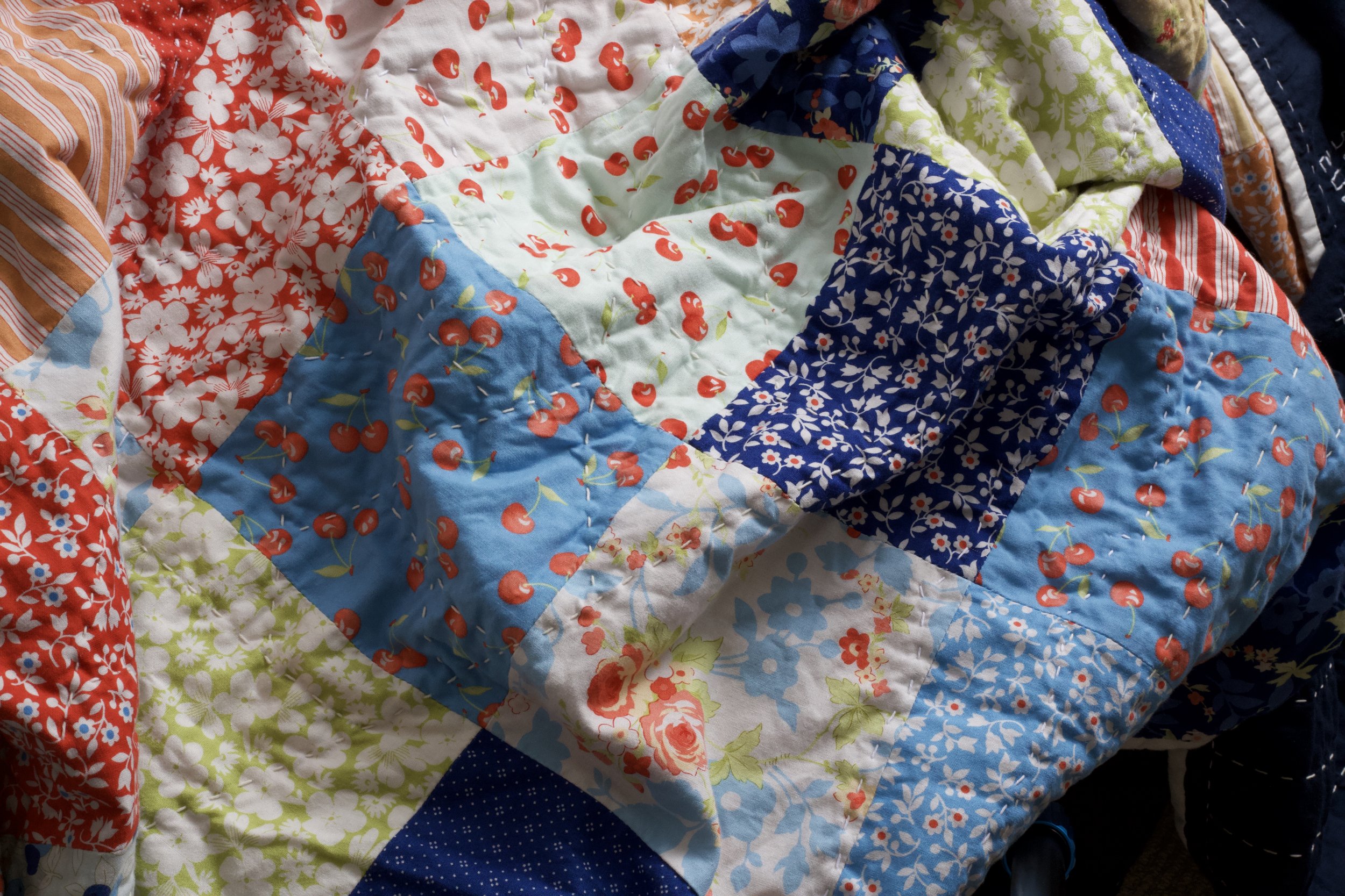 The quilt top-side is a deceptively simple square pattern with sashiko sneaking through from the back-side.