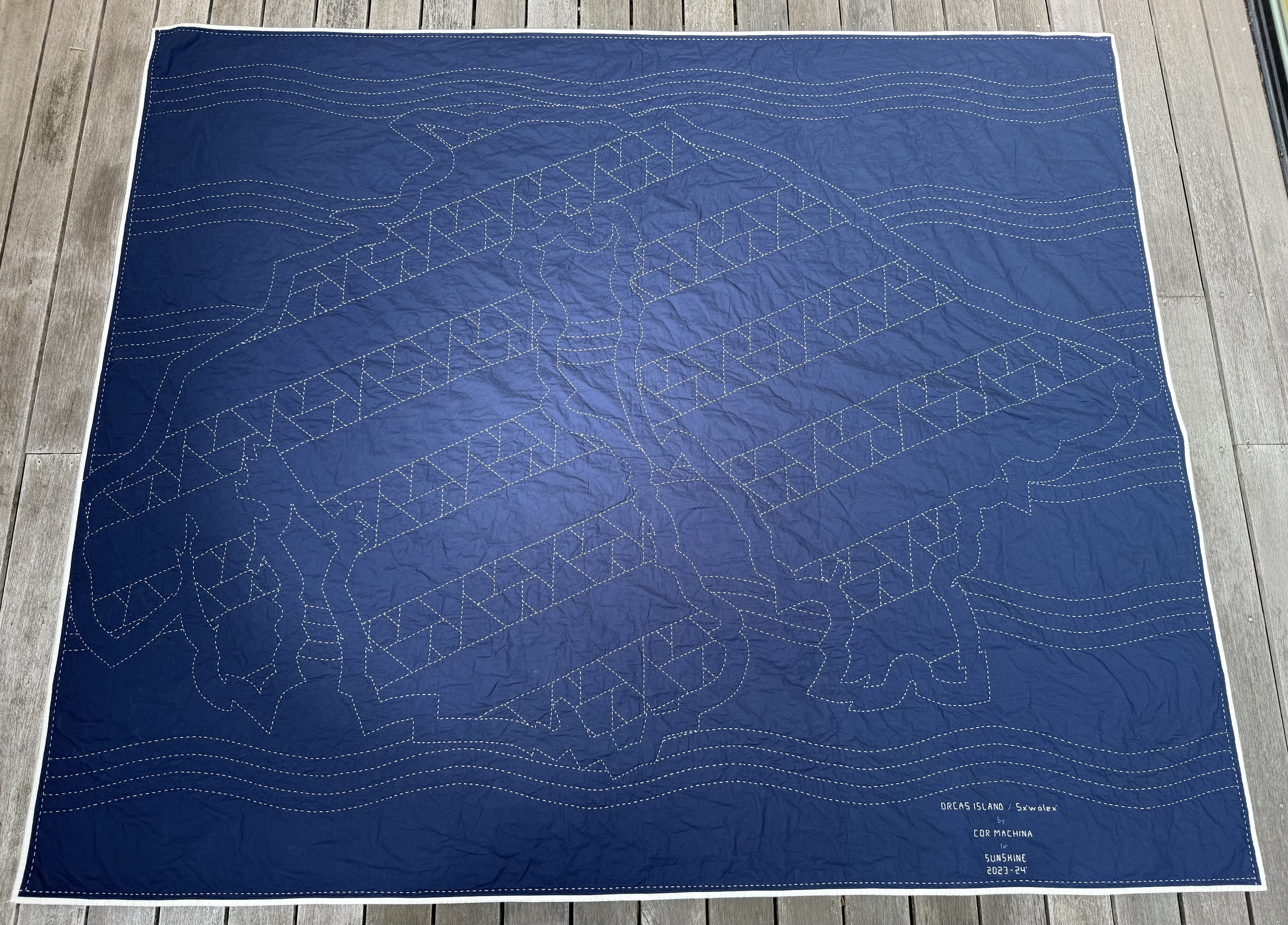 The full queen size quilt showing the map of Orcas Island in hand-stitched Sashiko
