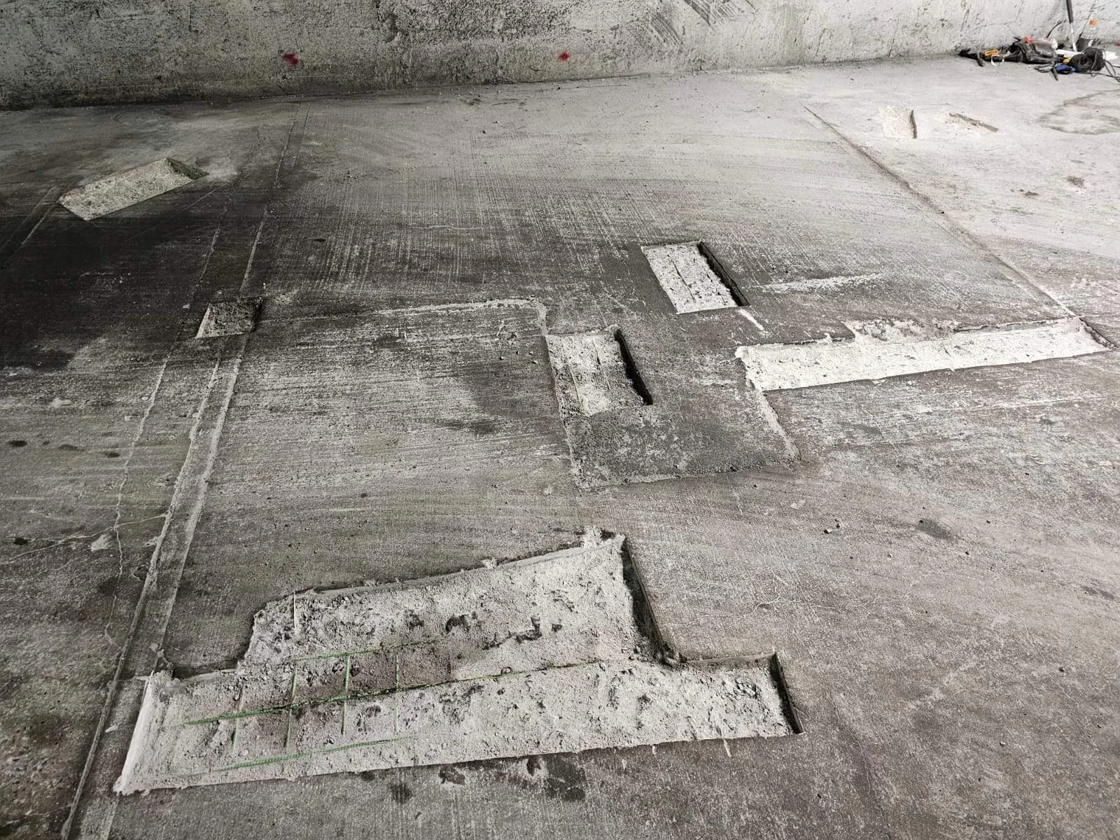 Construction site floor with partially removed concrete slabs, some with visible rebar and chipping edges.