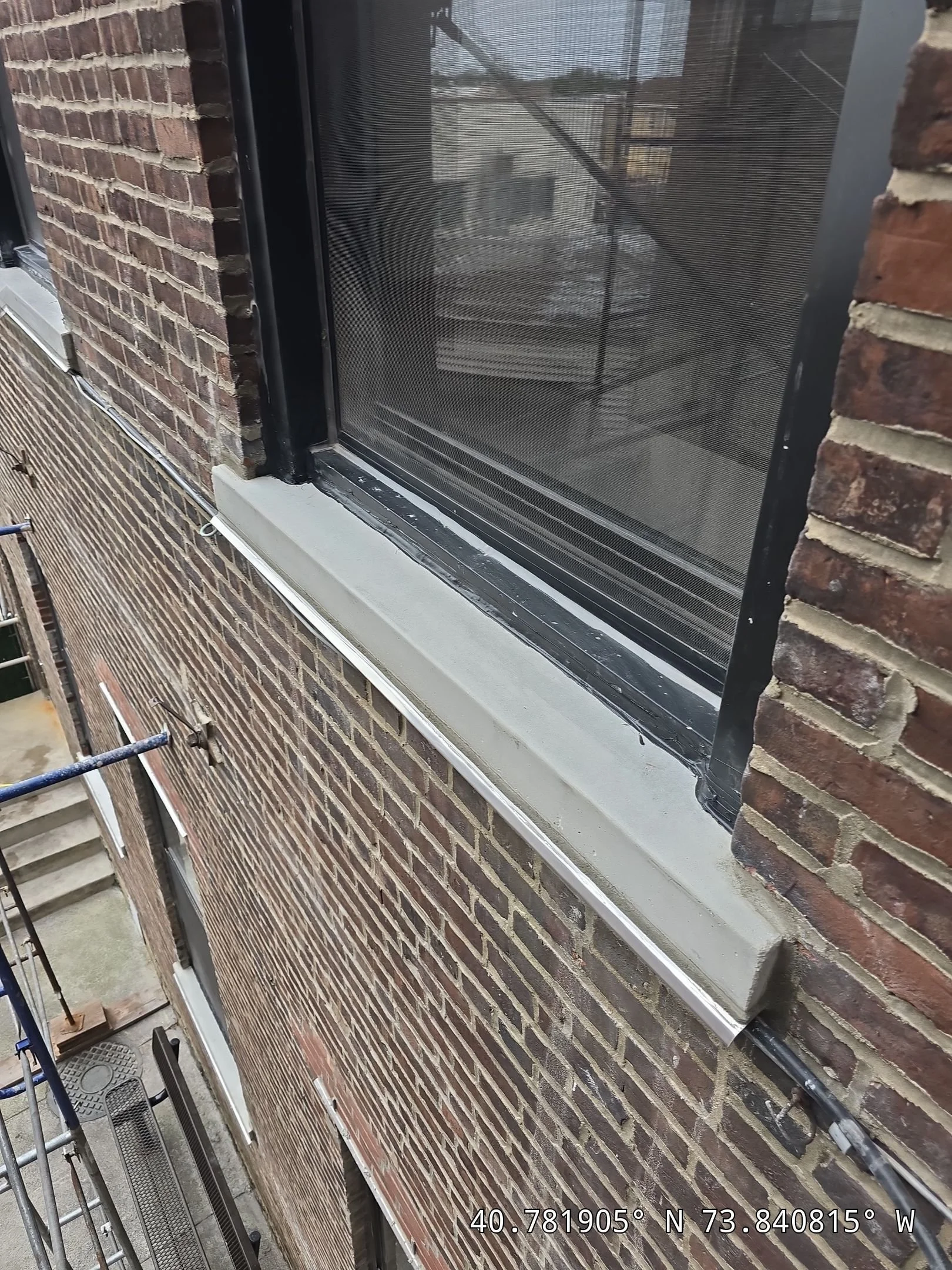 Close-up of a a nbewly installed pre cast concrete window sill with a newly installed metal window sill on a brick building