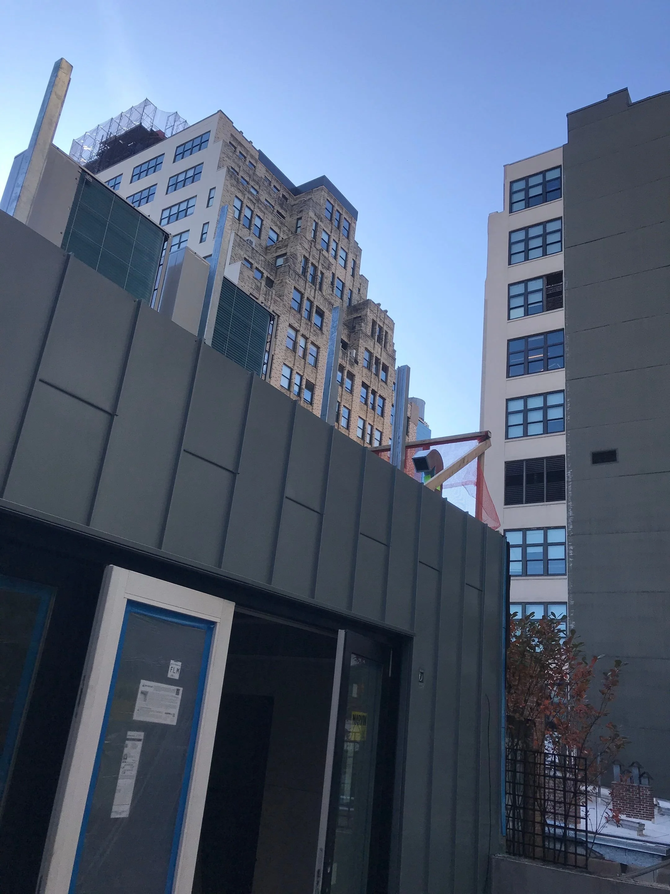 Cityscape with tall buildings, construction crane, and clear blue sky.