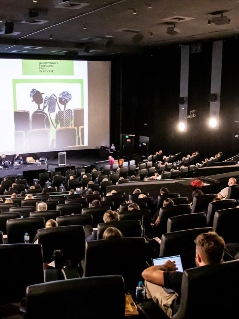 A crowd sits in a busy cinema space for the Australian Feature Film Summit