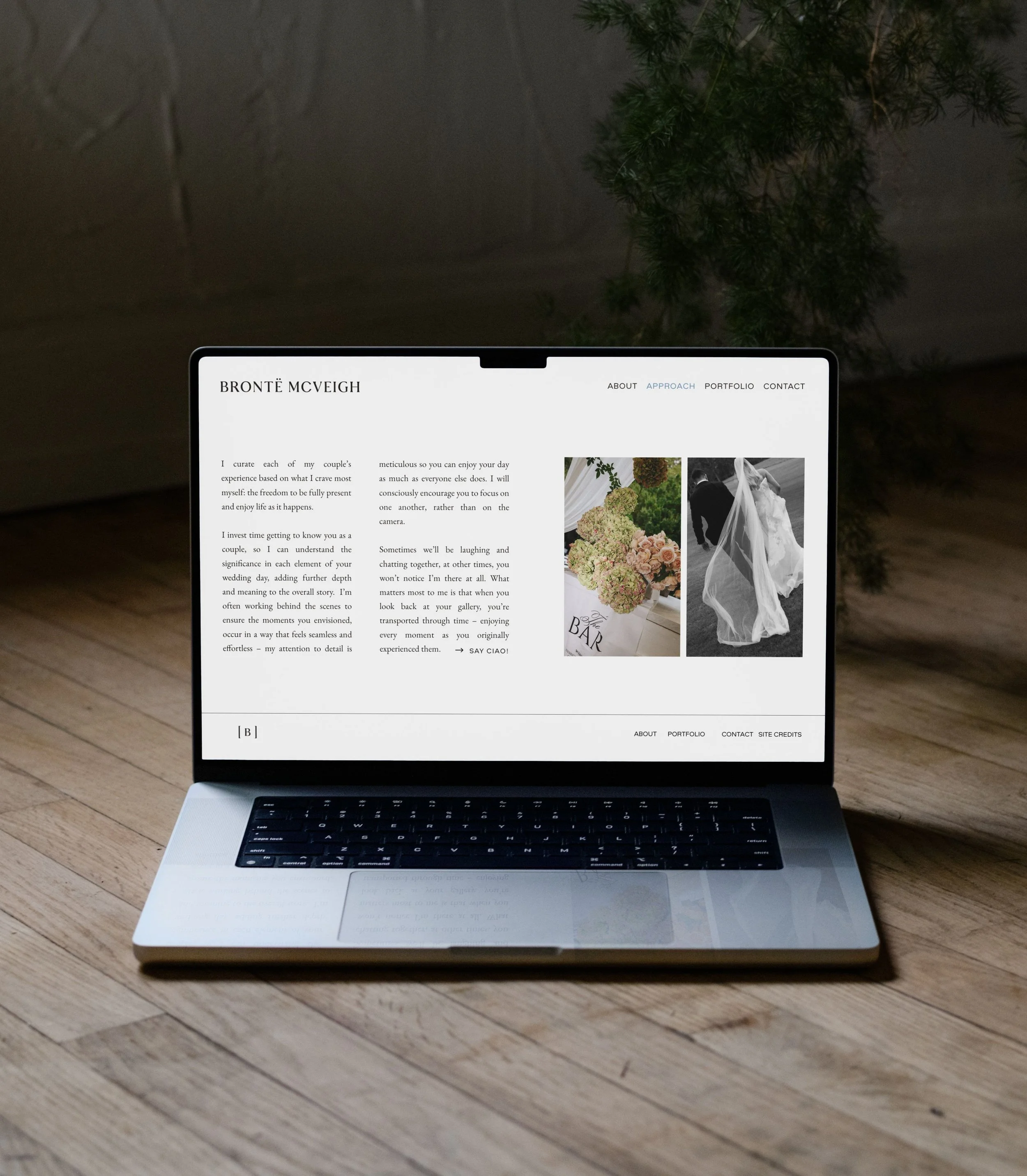 A laptop on a white bed with a website showing a baby photo and a navigation menu on the screen.