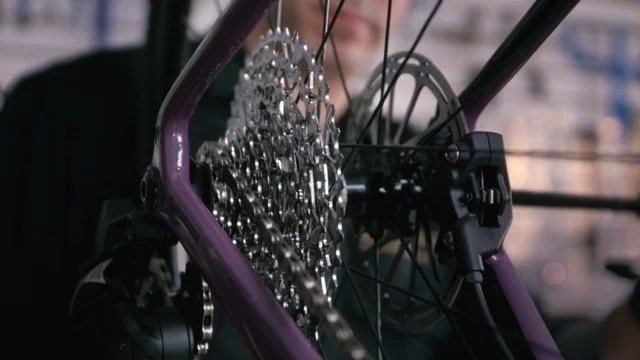 Vue rapprochée du dérailleur et du cassette d'un vélo, avec un cadre violet en arrière-plan.