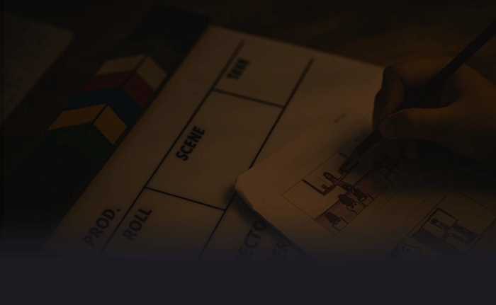 Prise de vue d'une planche à dessin ou scénario pour un film, avec une main utilisant un pinceau ou un crayon, sur une table en bois.