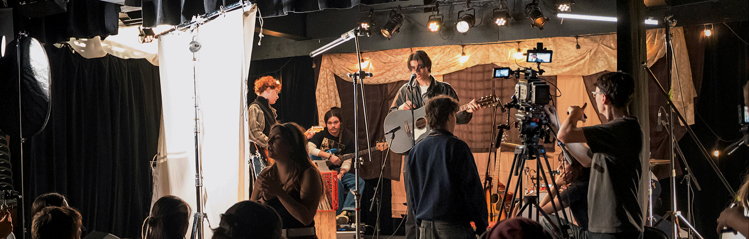 Un groupe de musiciens enregistrement dans un studio avec des caméras et un éclairage professionnel.
