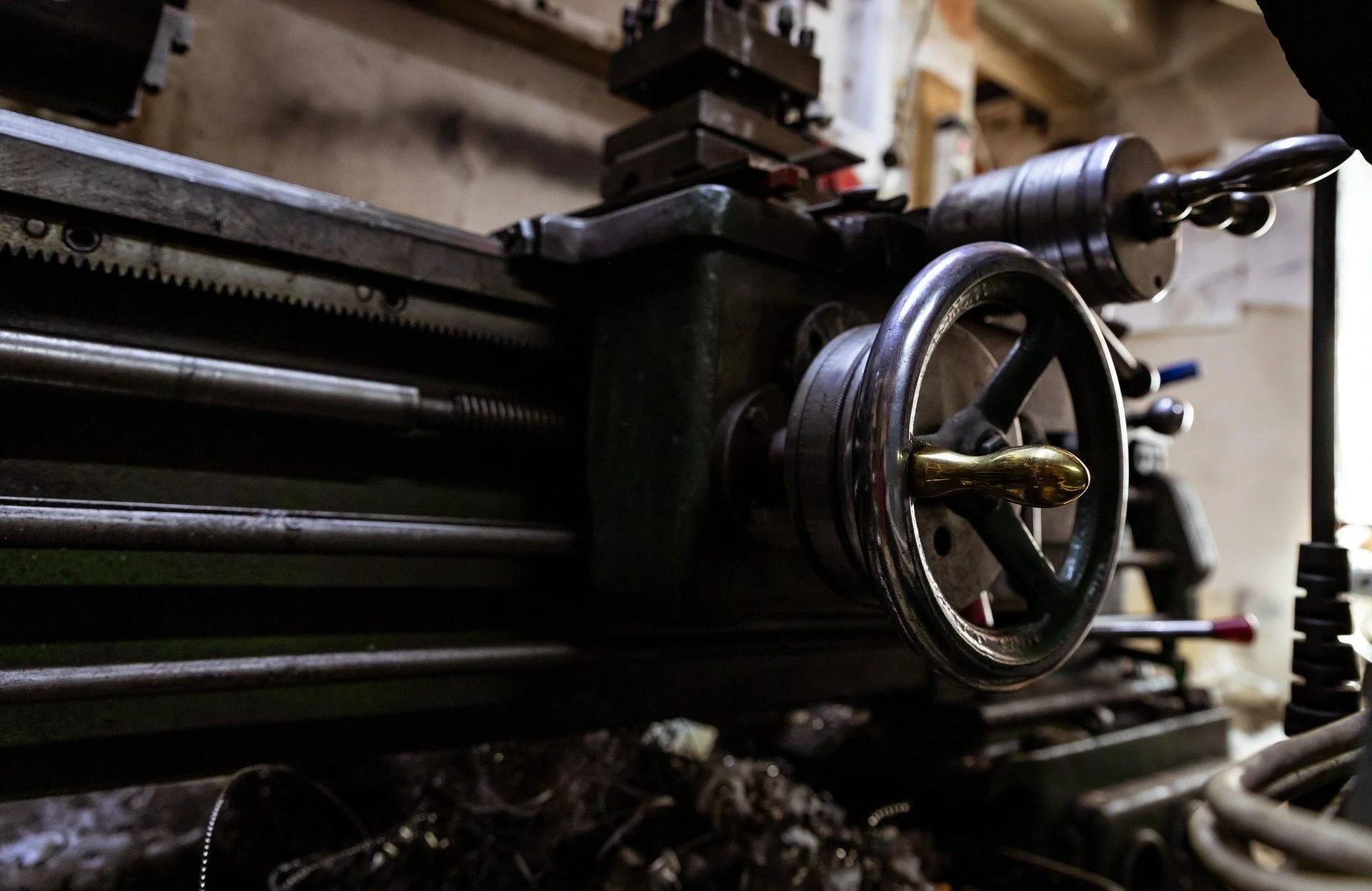 Scenic view of a lake with turquoise water surrounded by grassy hills and distant mountains under a cloudy sky.