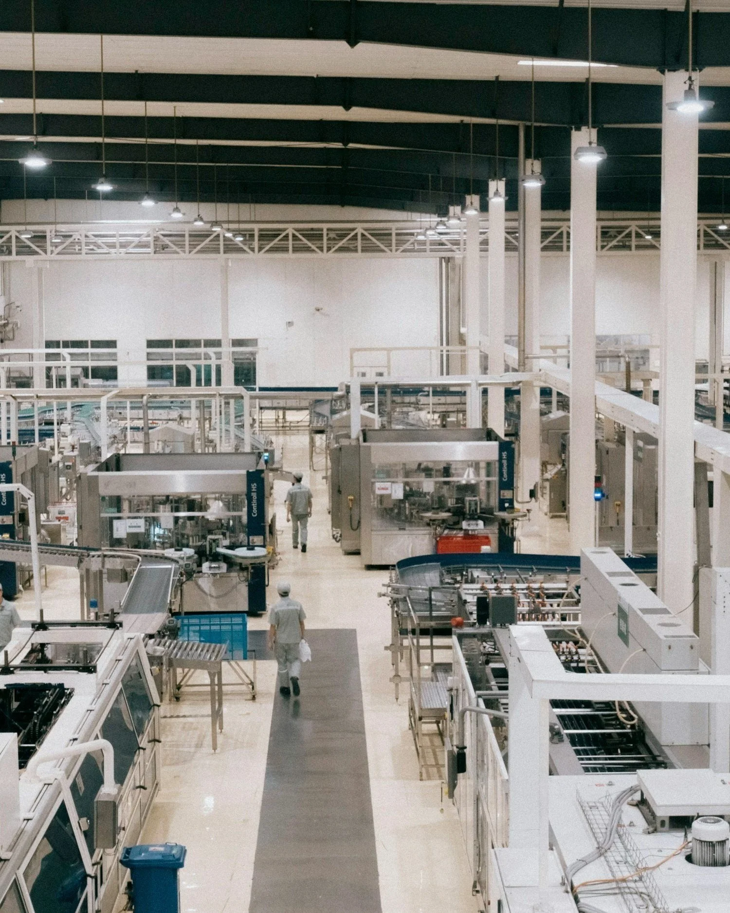 Inside a modern, spacious food processing or manufacturing facility with workers and industrial machinery.