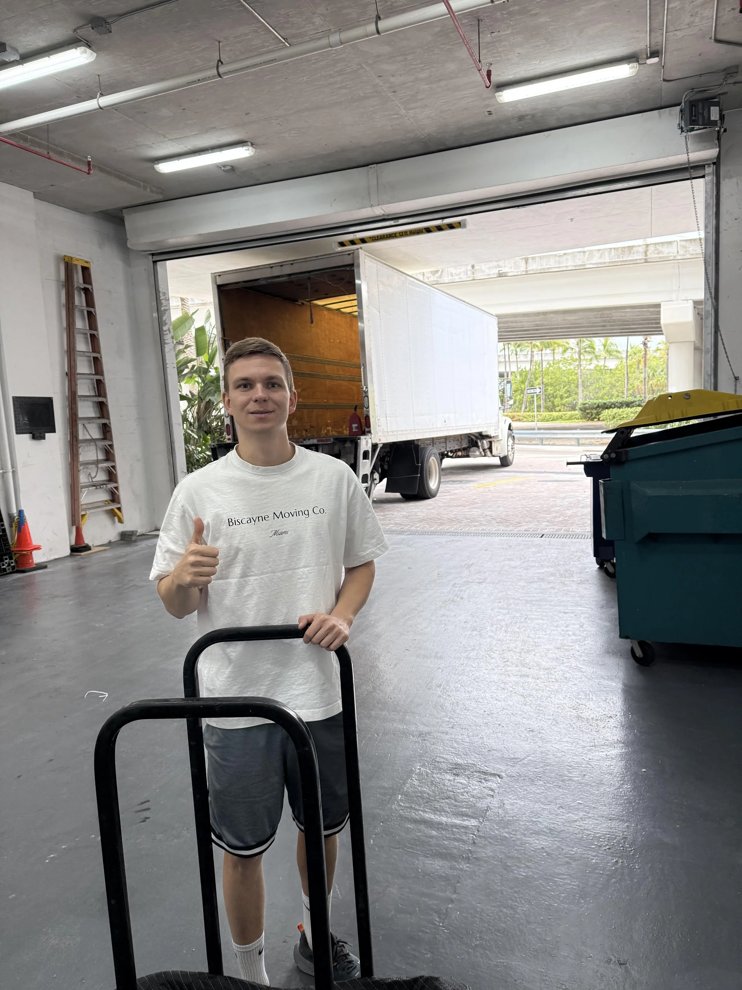 Uniformed local mover with dolly standing in front of moving truck in Sunny Isles Beach