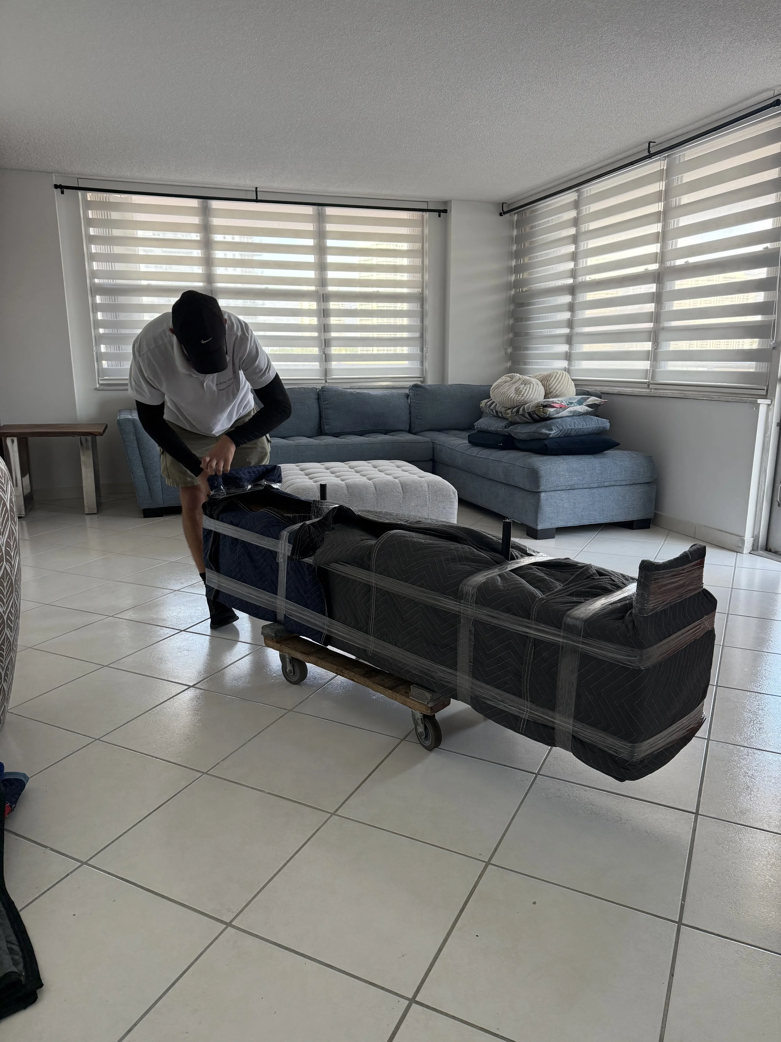 White glove mover carefully wrapping a TV stand during a local move in Miami
