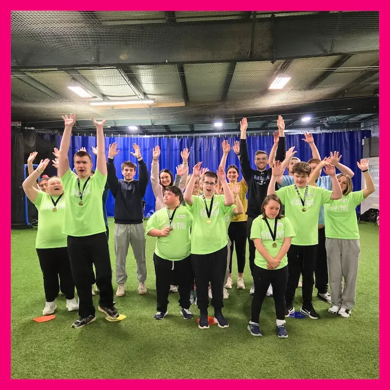 Group of smiling kids in orange High Five shirts pose together in a gym, representing friendship, and youth empowerment through The Champion Project, Sports Programs for athletes with disabilities in Western New York
