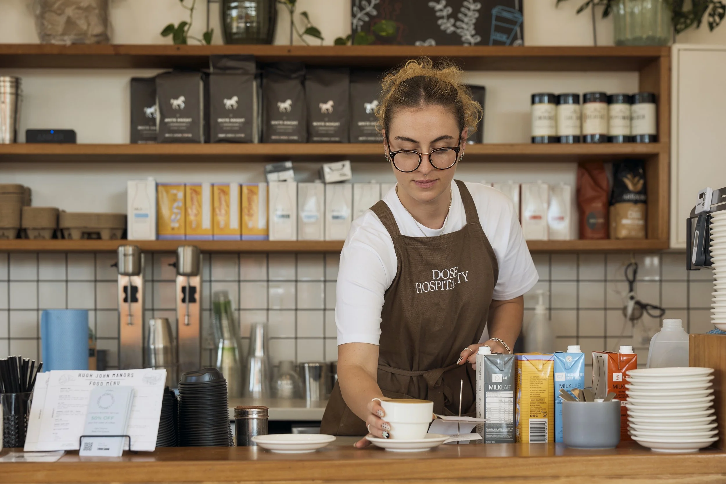 Barista at Dose Hospitality café preparing and serving fresh coffee in Sydney