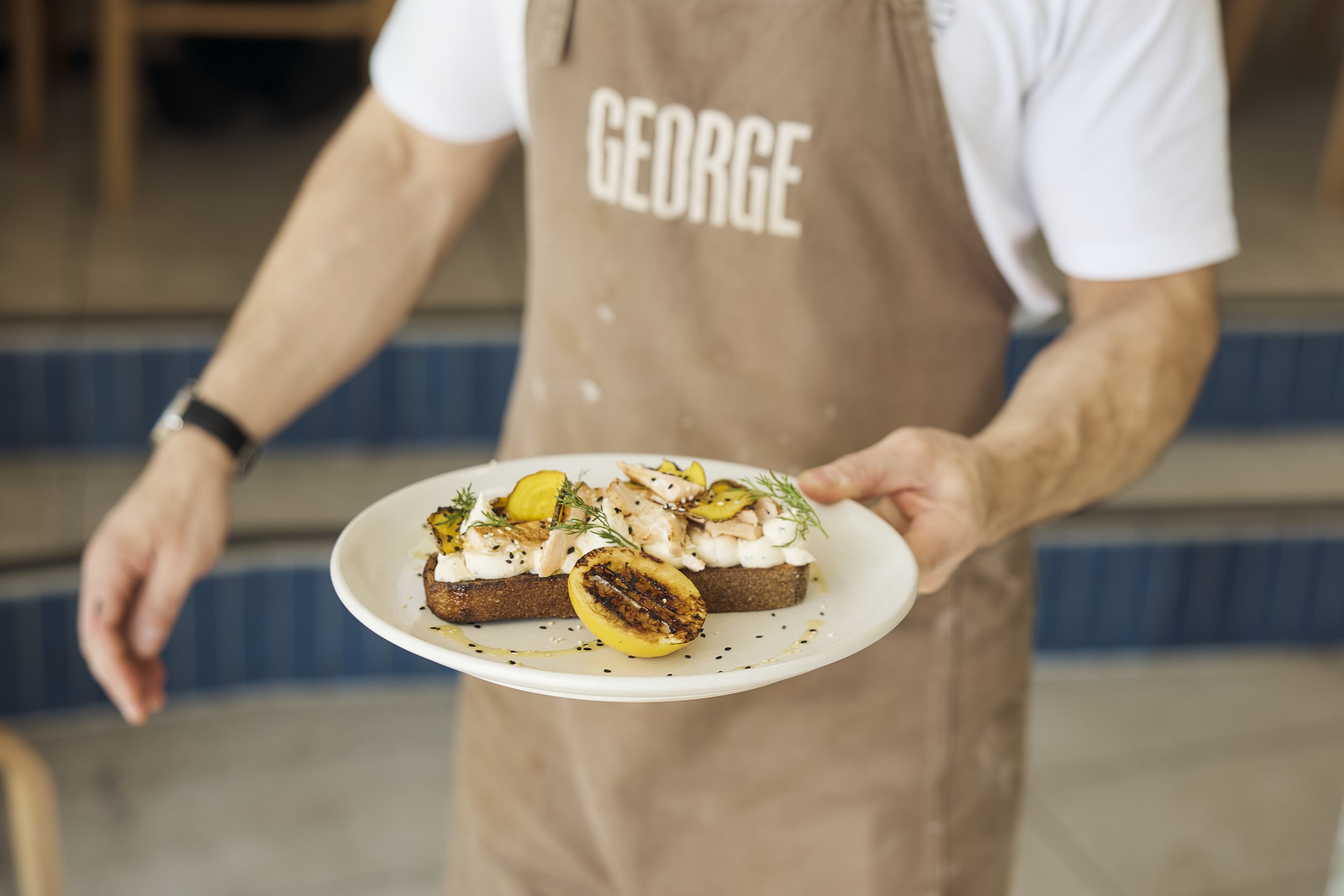 Dose Hospitality staff at George Oyster Bay café serving gourmet toast with grilled lemon
