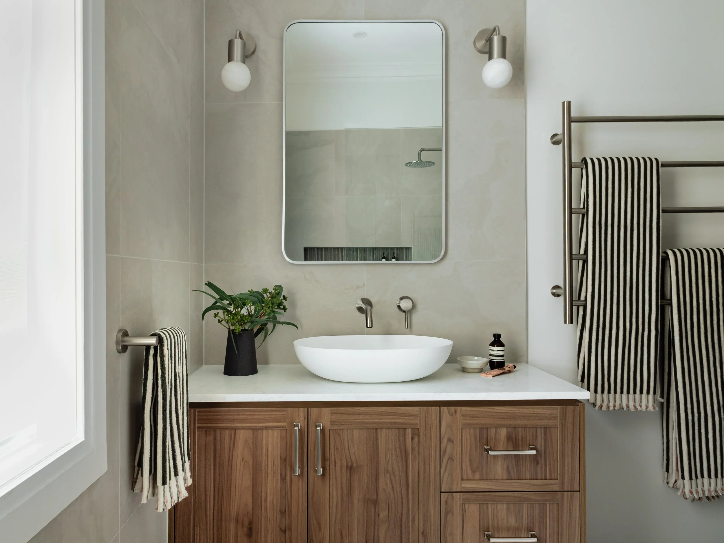 Wide view of bathroom sink, mirror, towel rack. Stone, wood, metal, earthy, contemporary interior design. 