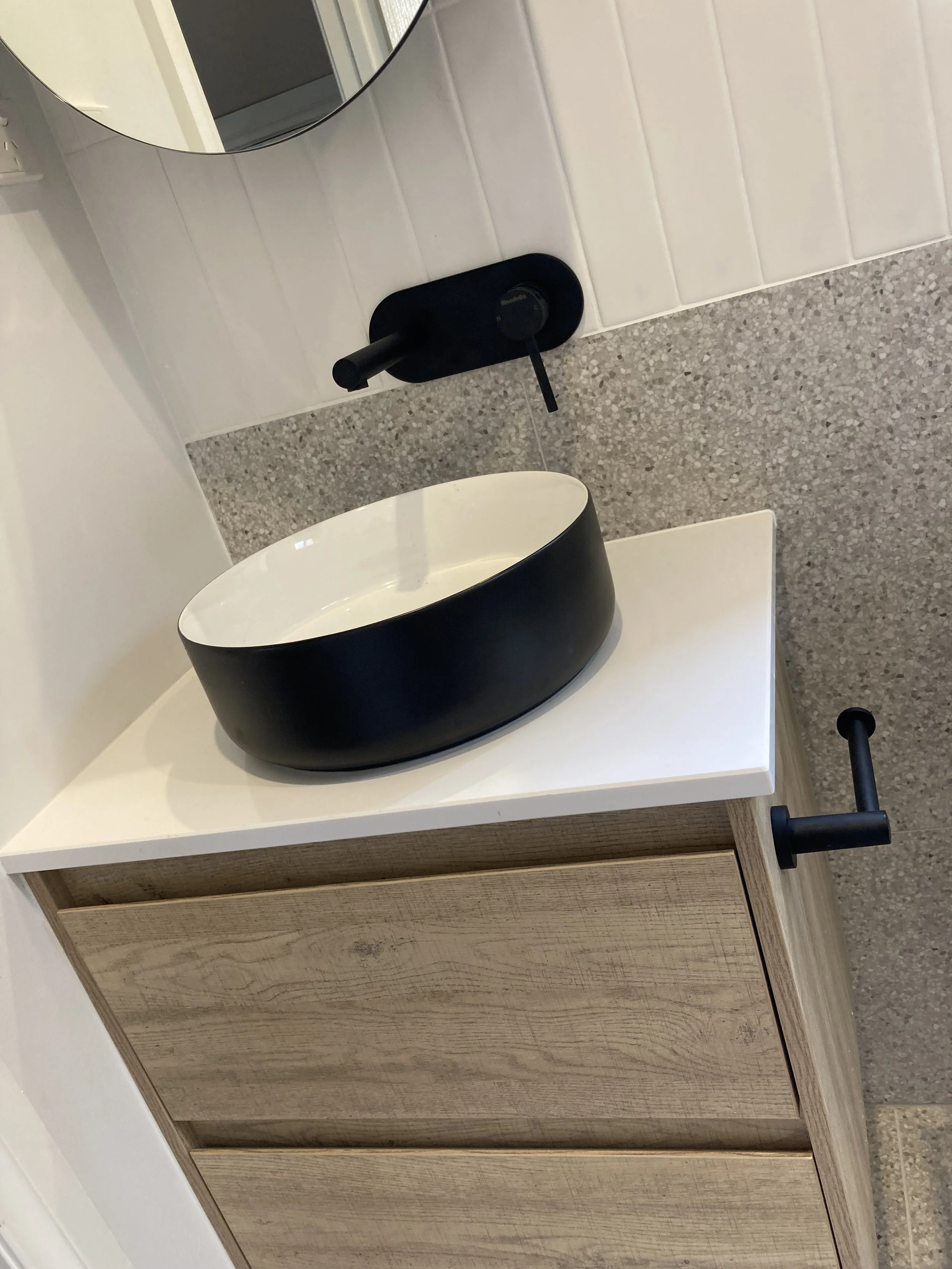 Angled photo of vanity, showing the black and white basin and black fixtures.