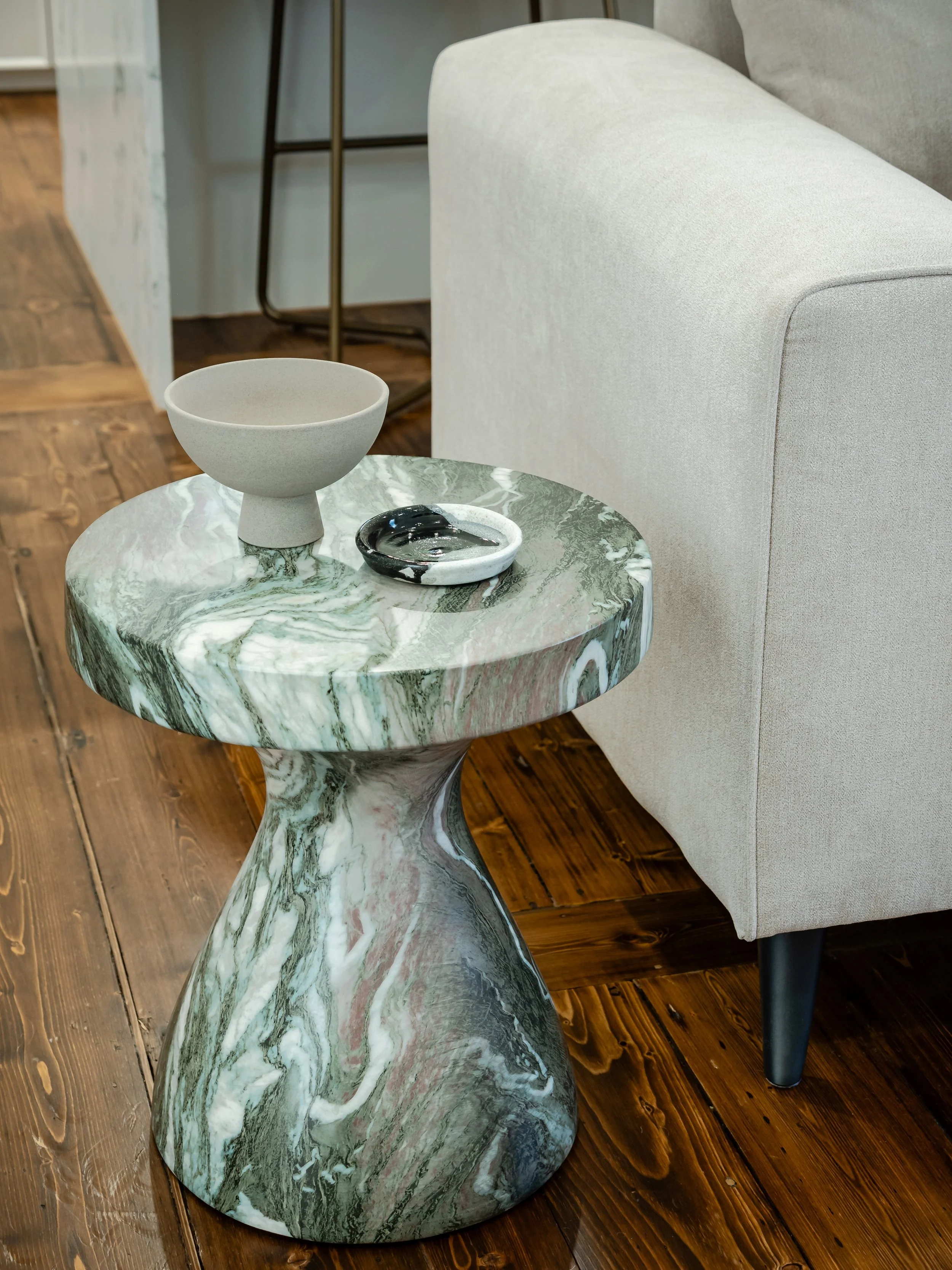 the stone end table with bowl and dish, sitting on wooden floor in living area 