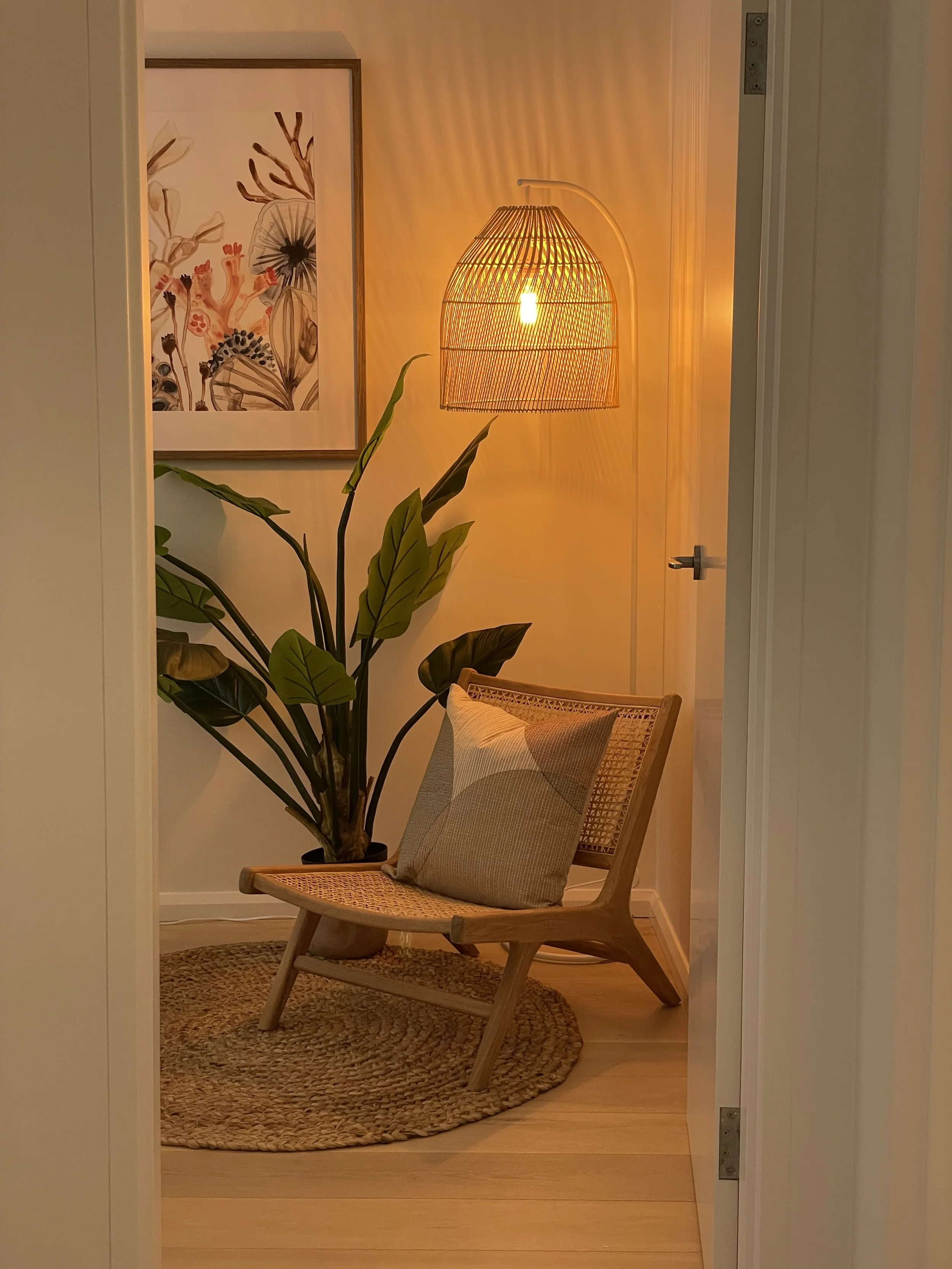 Wooden folding chair with decorative cushion and plant. Rattan lamp.