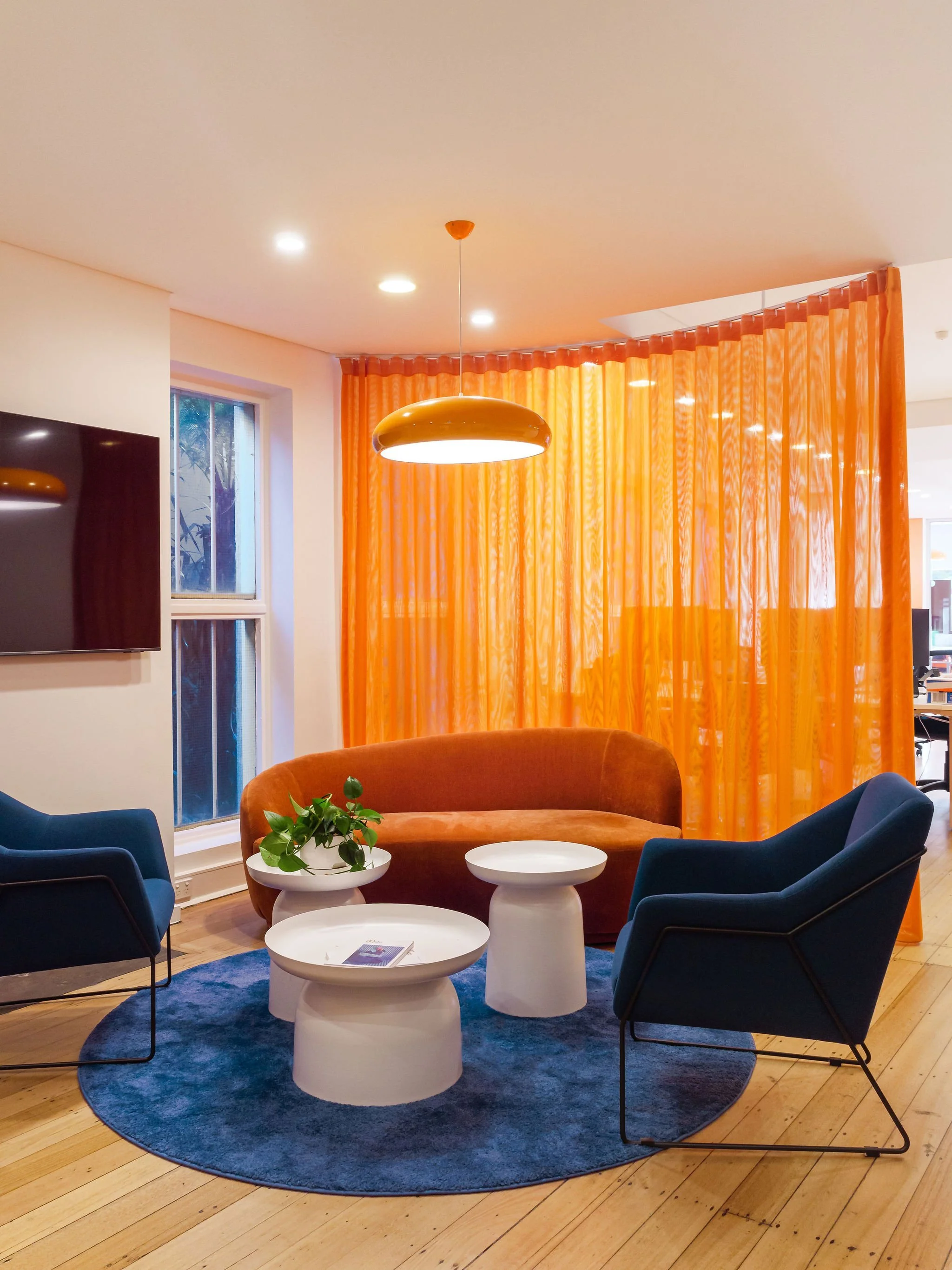 Wide view of the sitting and collaboration area, with orange and blue furniture.