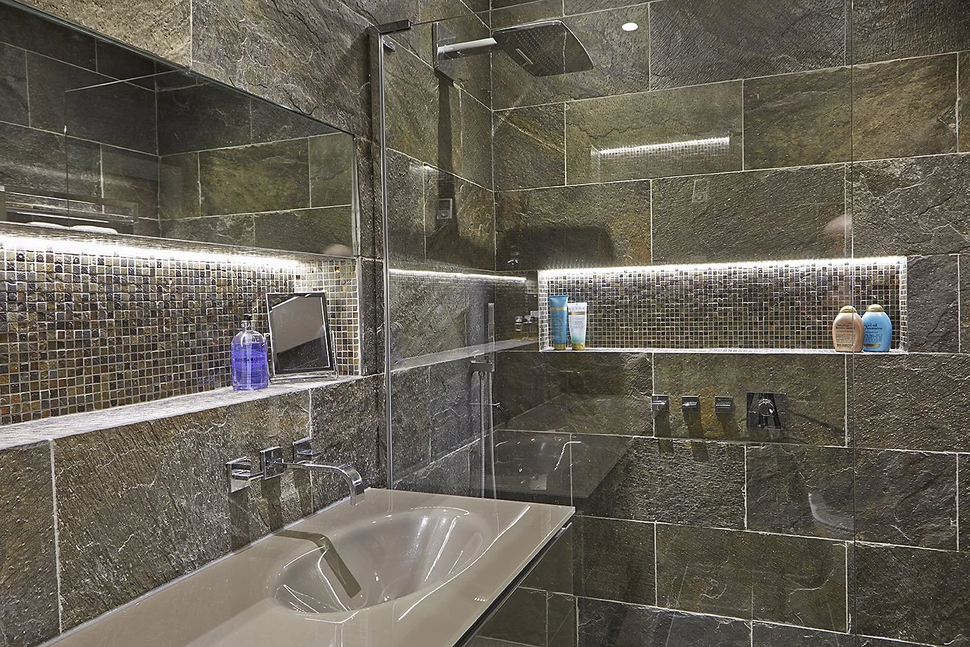 contemporary bathroom wall with green tiles, sink, and shower with inset shelf 