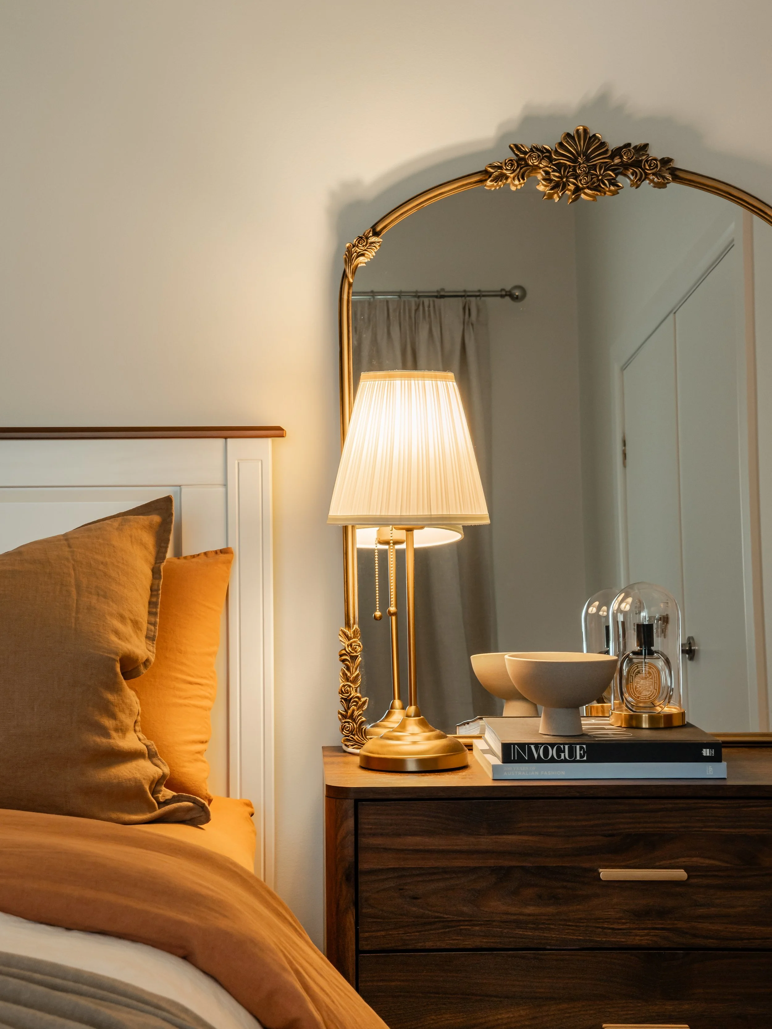bedroom side table with illuminated lamp, wooden table, earthy yellow bedding in Brunswick East home 