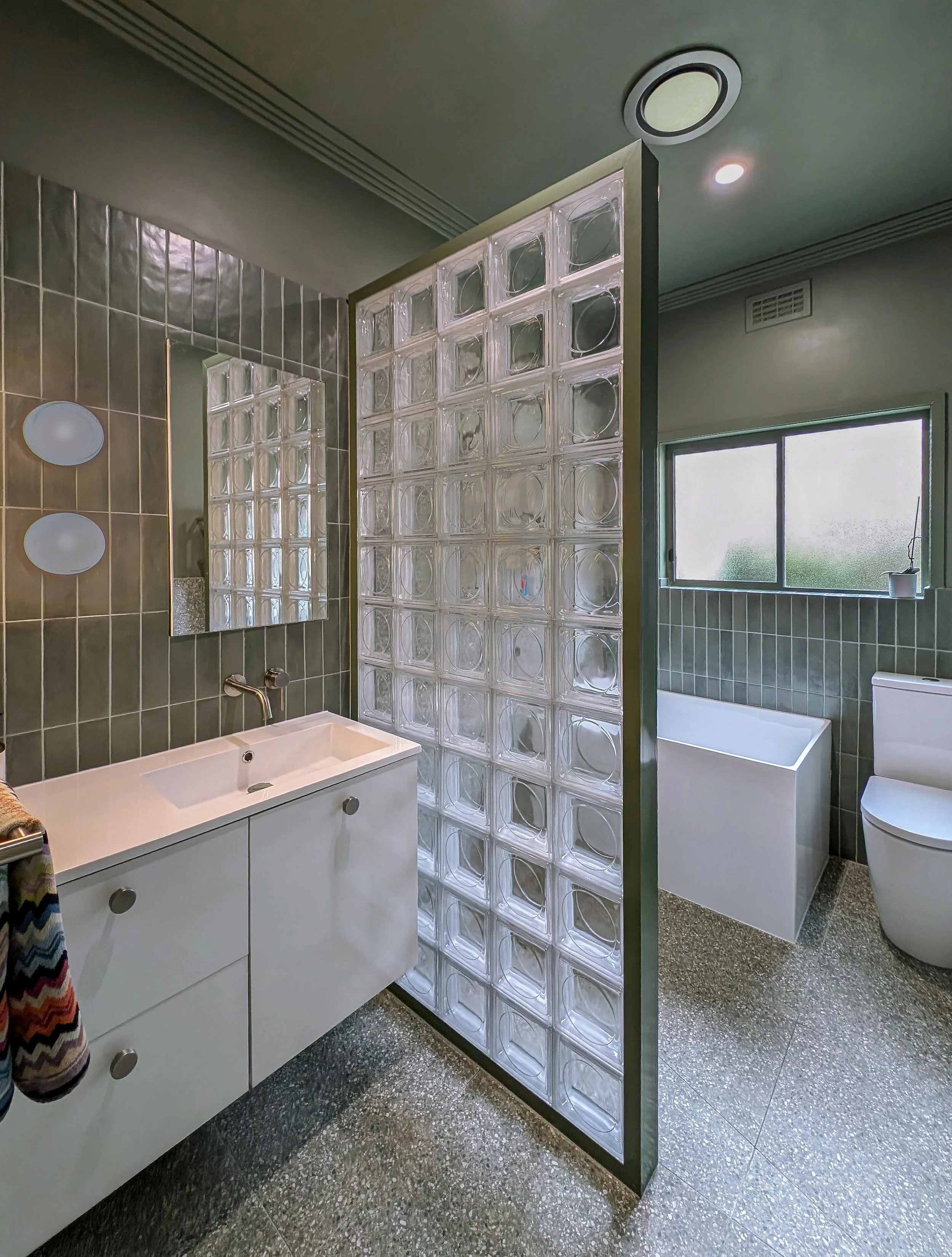 wide shot of bathroom in Brunswick family home, showing the glass wall and modern fixtures of a modern interior designed home 