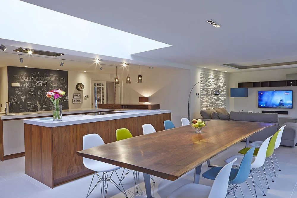 wide view of modern, open plan kitchen, dining, and living space, compelemented by bright colours