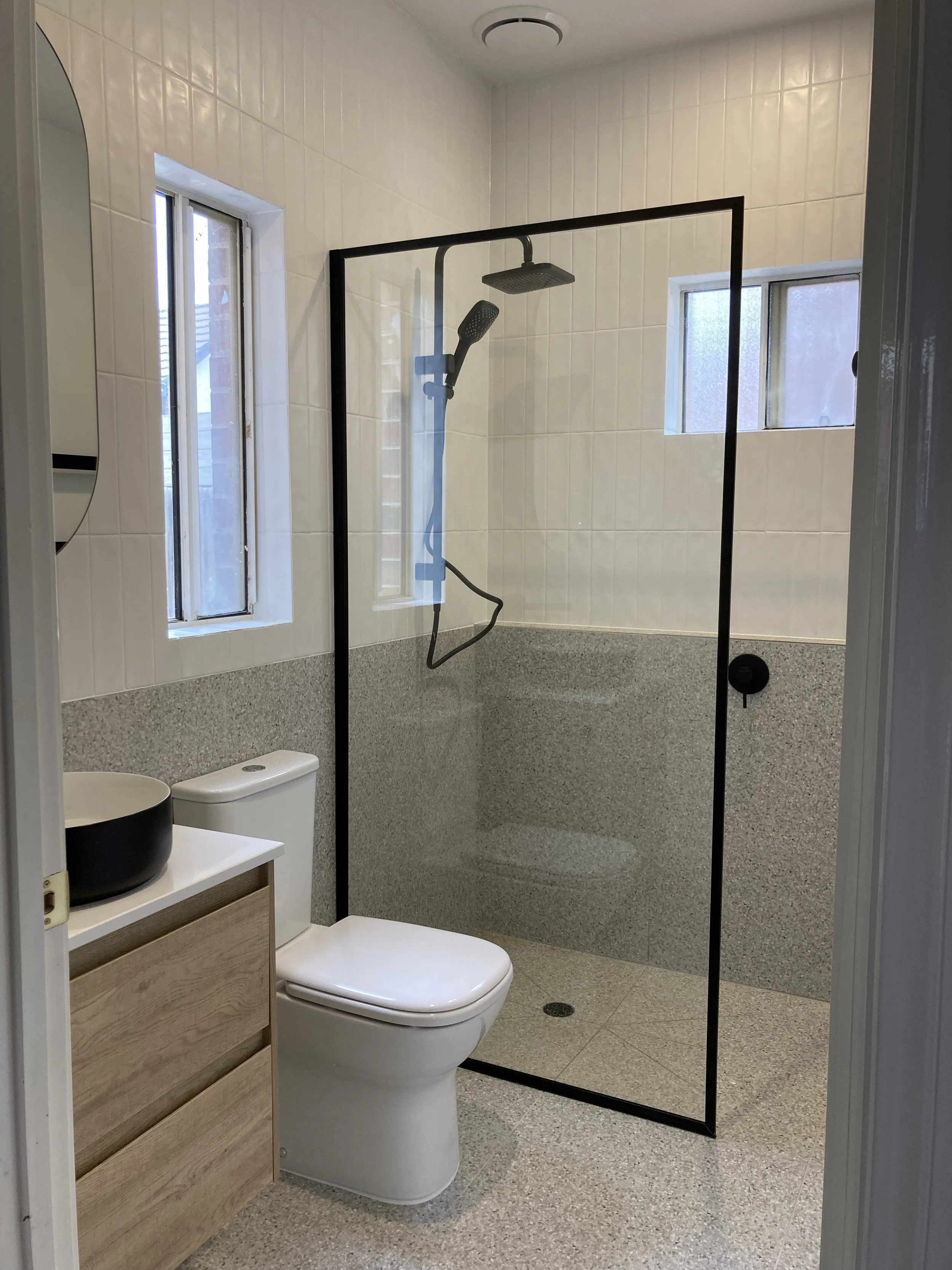 view of converted laundry to bathroom, showing sink, toilet, and shower.