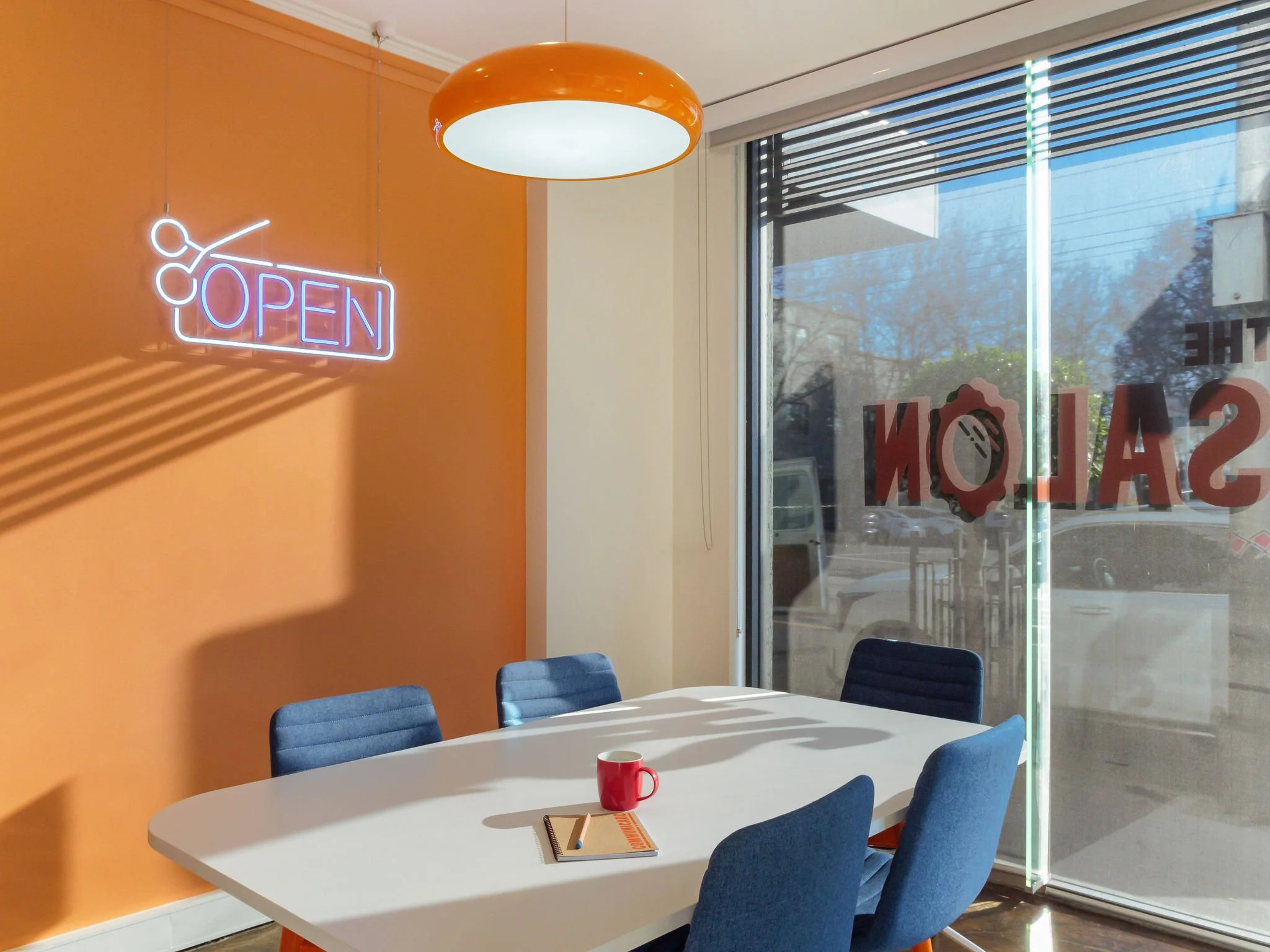 Commercial building interior converted for workspace. Meeting room with repurposed salon signage. Meeting room with table and five chairs.
