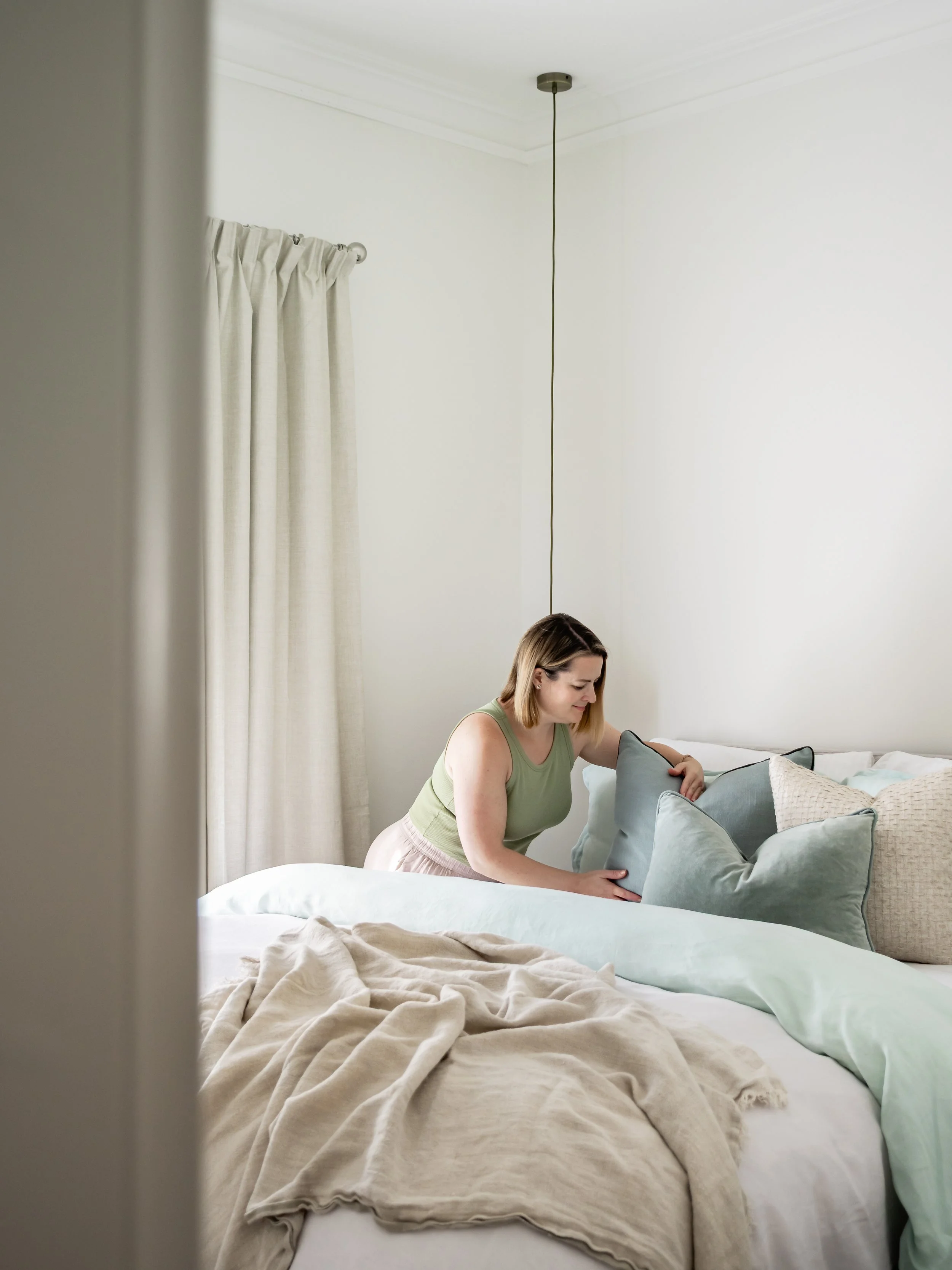 Catherine Hamer, laying the final touches on the neutral, minimal, contemporary bedroom in Brunswick East 