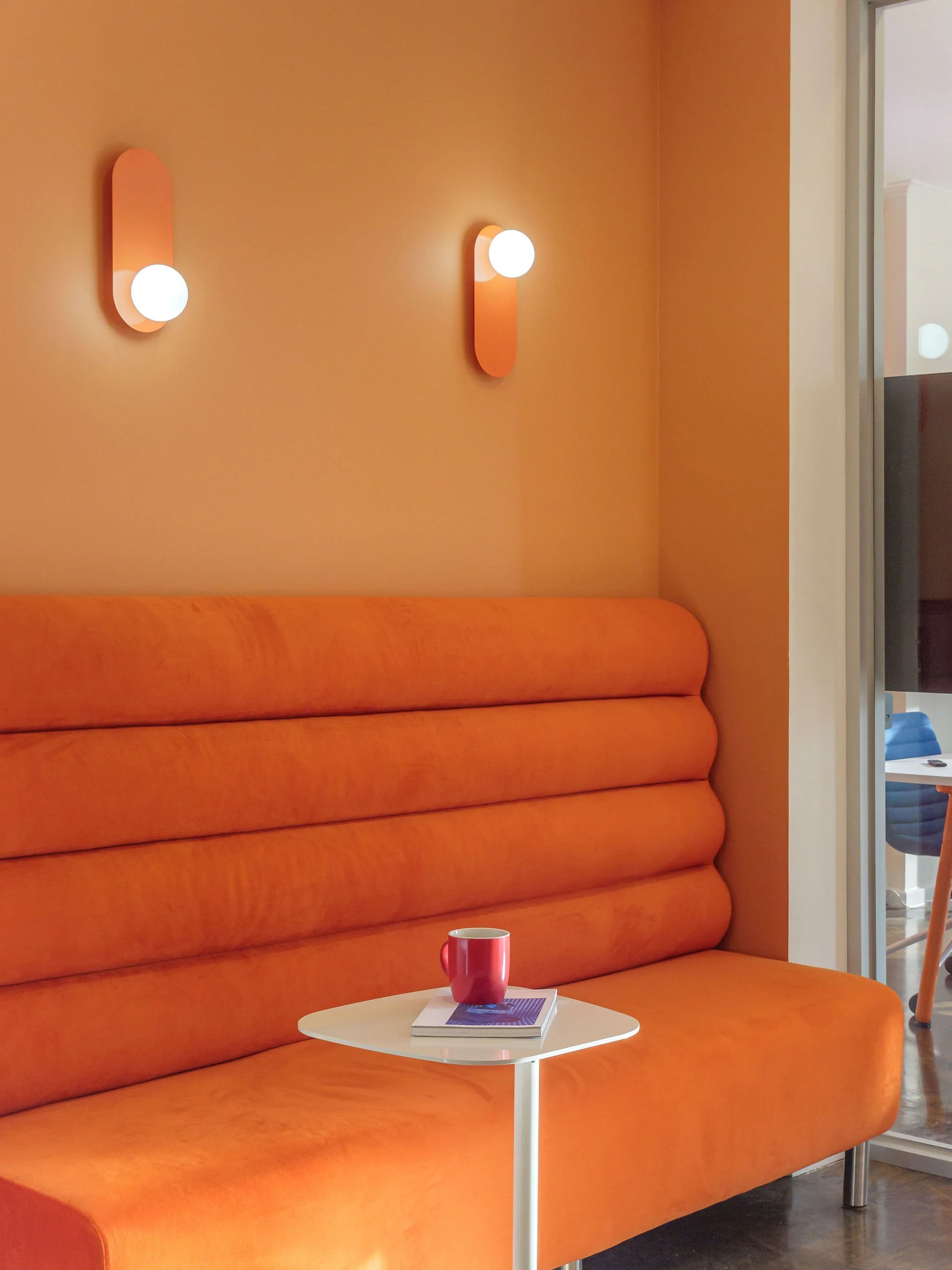 Big orange couch with white mini table.