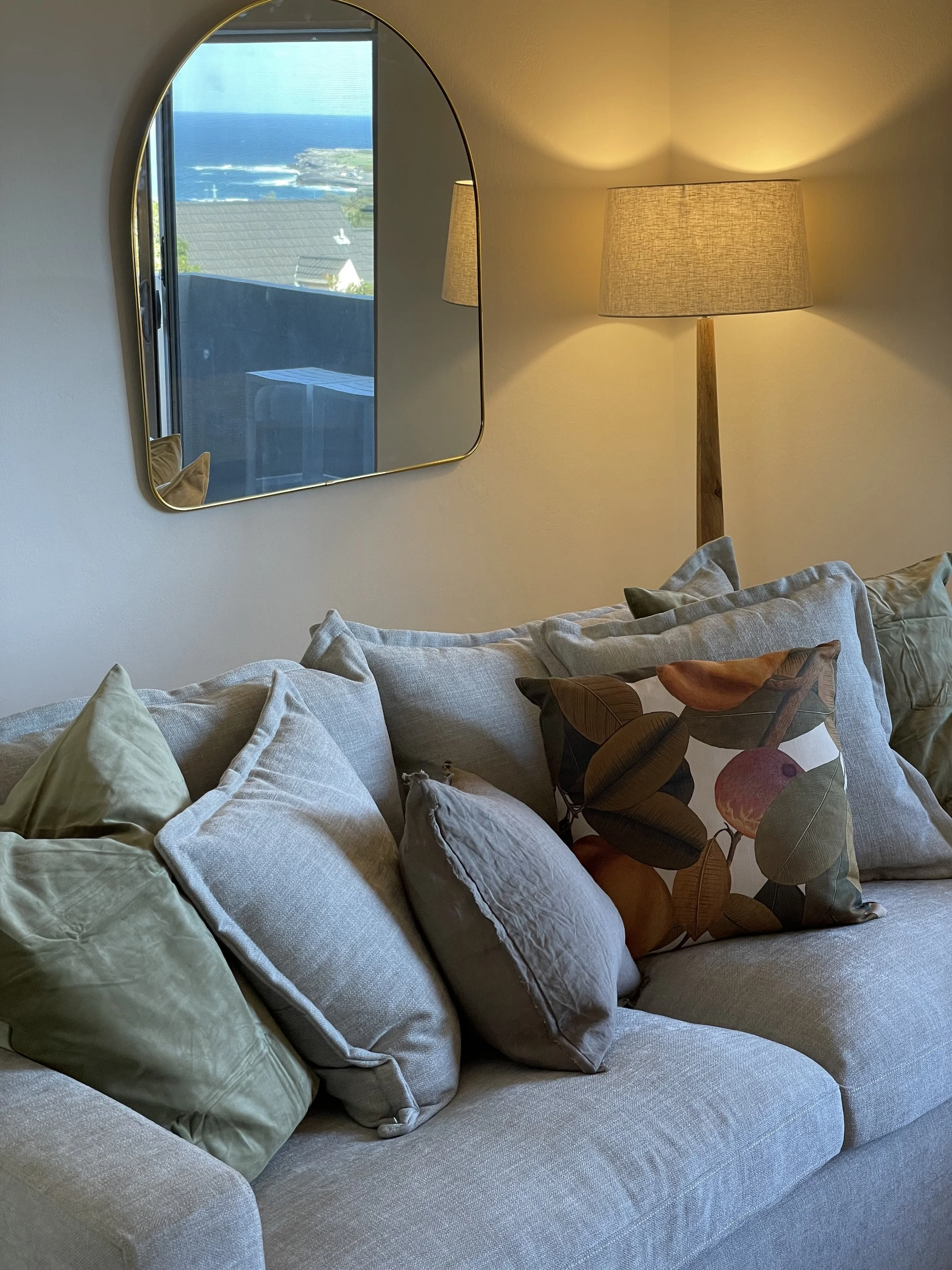 detail shot of the couch cushions, stone gray with one colourful leaf pillow to give it character