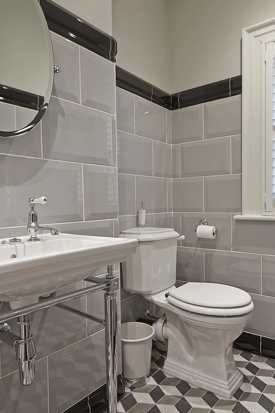 Angle of the bathroom showing sink and toilet, pale gray wall