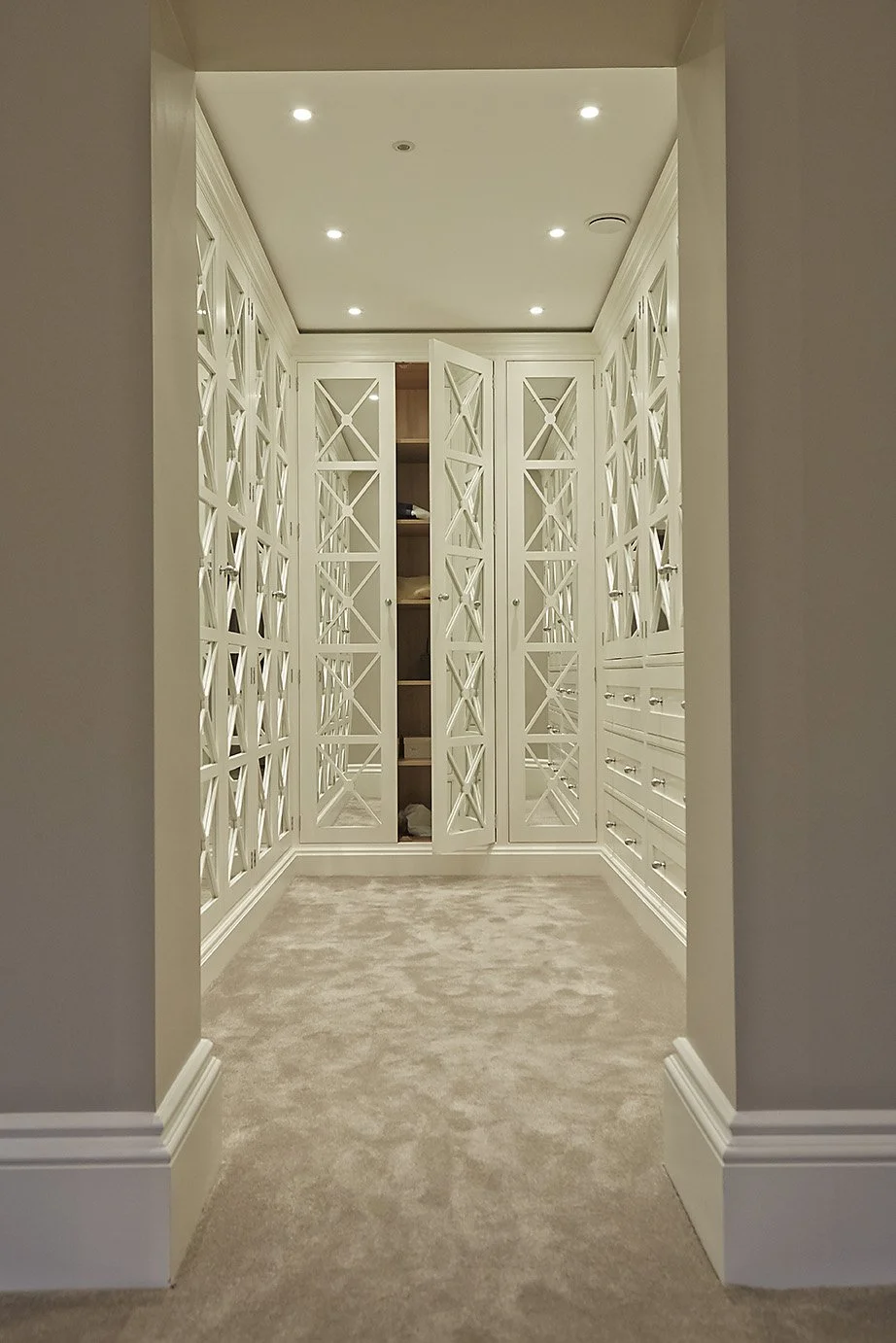 Walk in wardrobe with white, latticed, mirrored doors