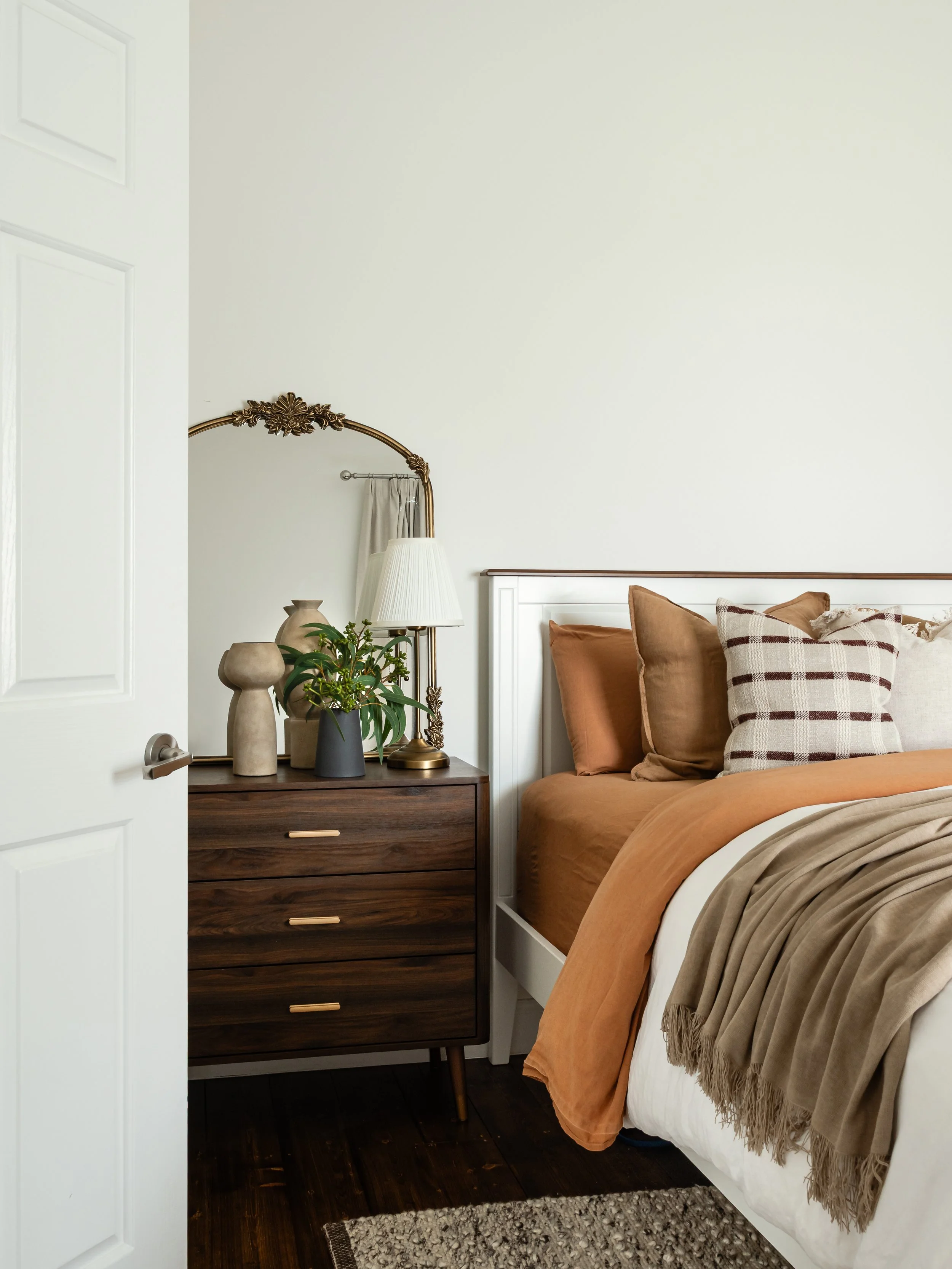 view from bedroom door of bed with soft, earthy colours, rug and bedside table, contemporary design 