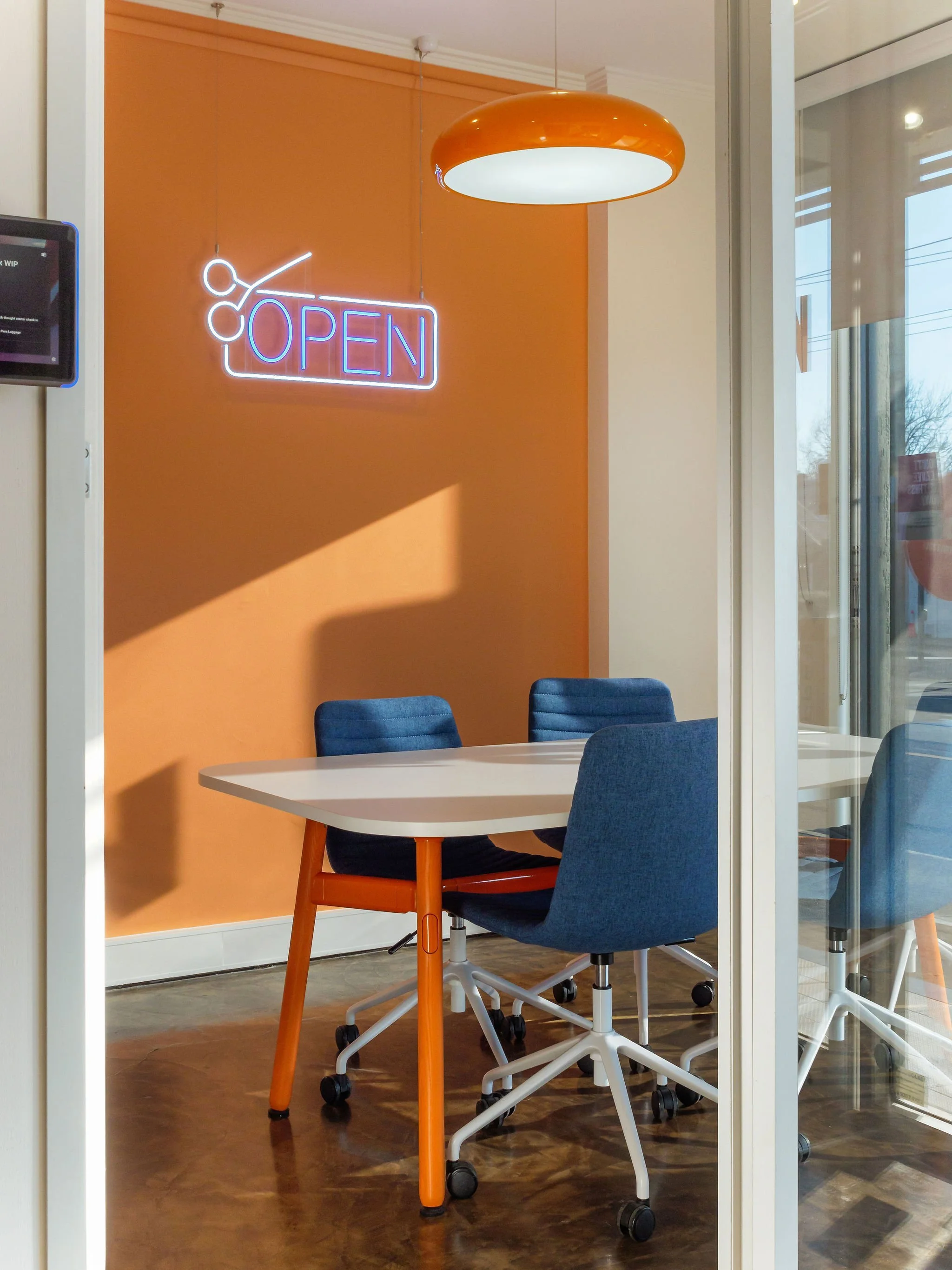 Creative media agency meeting room. Functional table with office chairs. Neon sign with OPEN text.