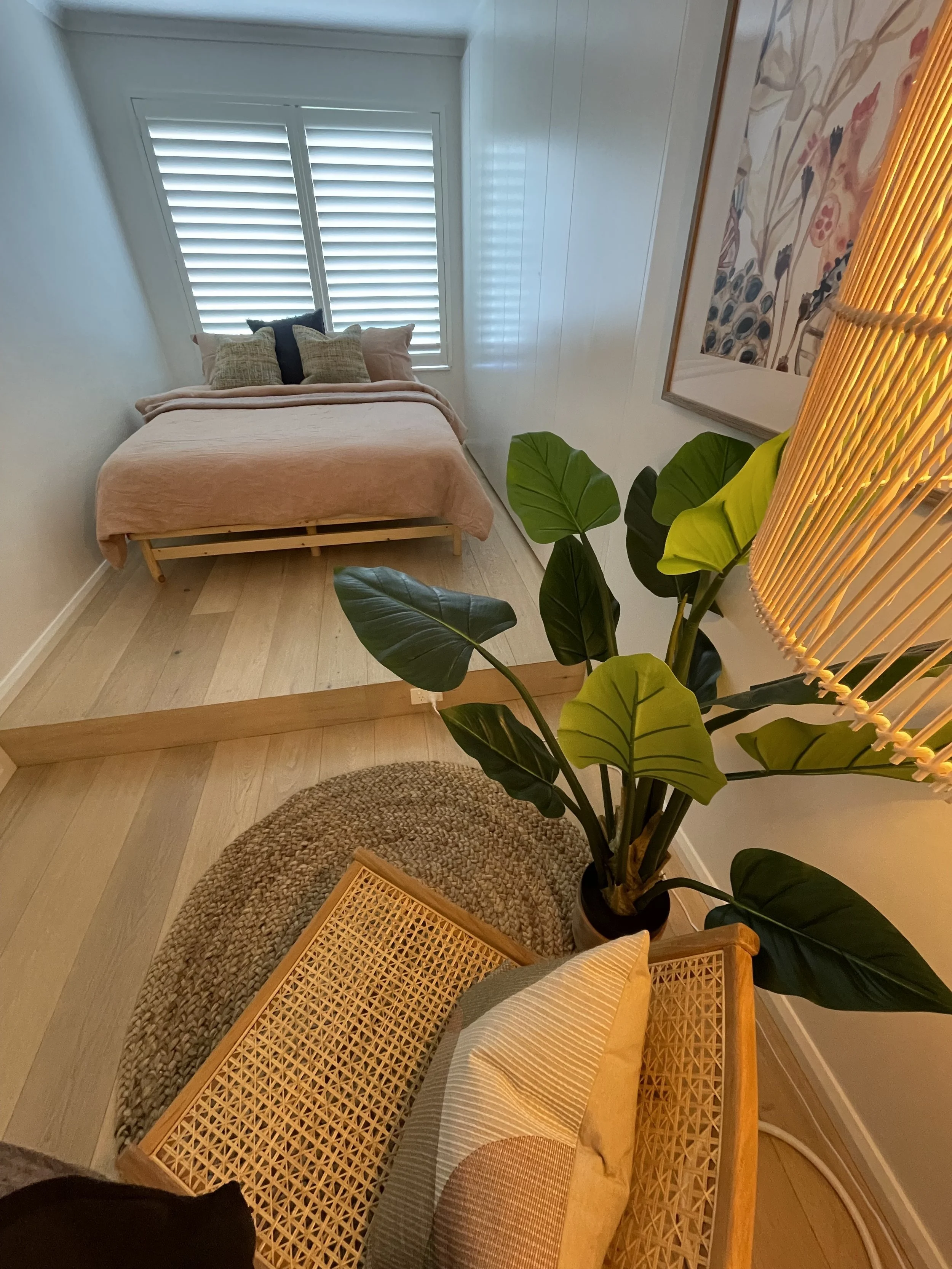 cozy sleeping area with soft colours, accented with a deep green plant 