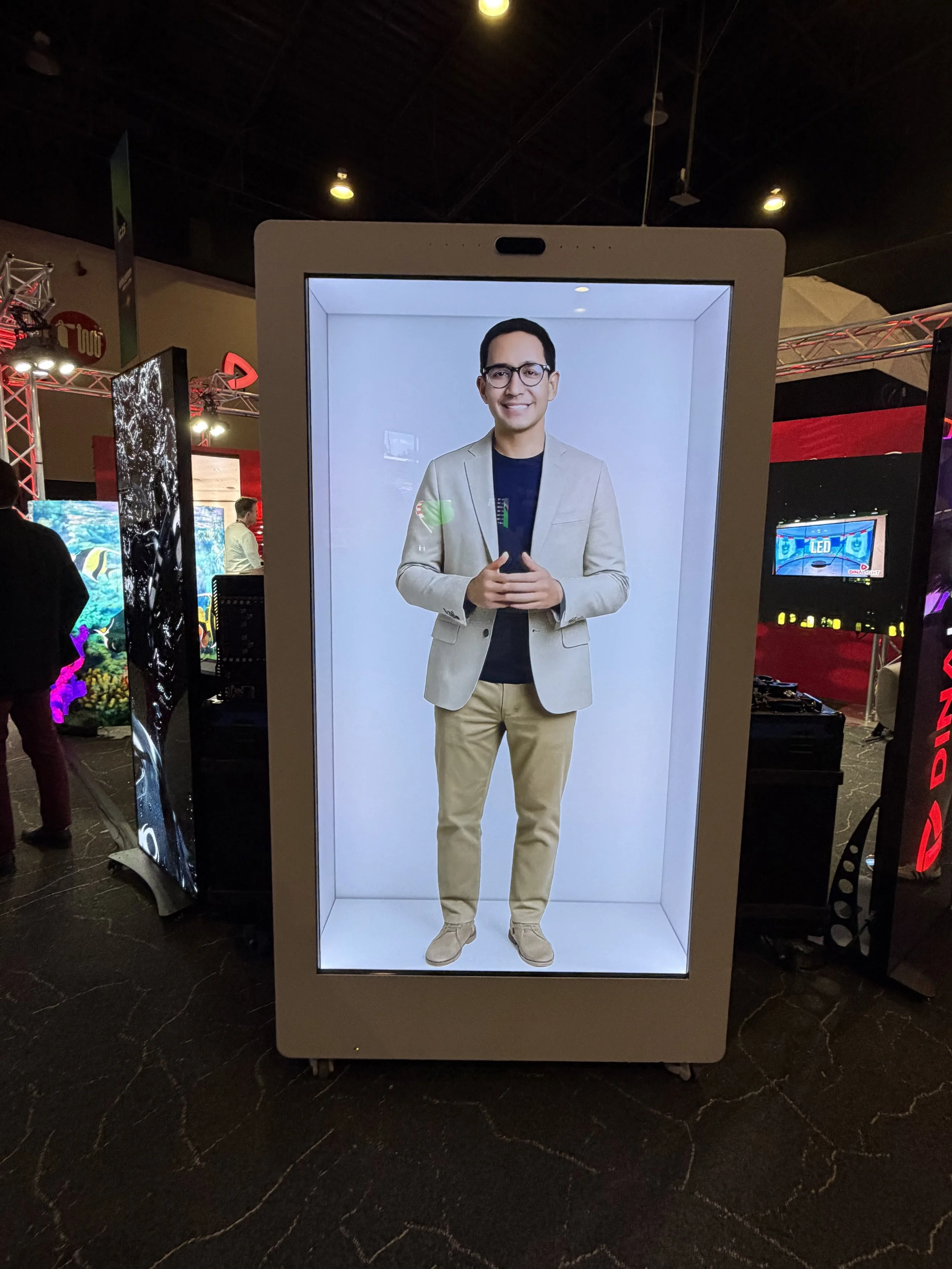 Hombre sonriente con blazer y pantalón claro en una caja LED