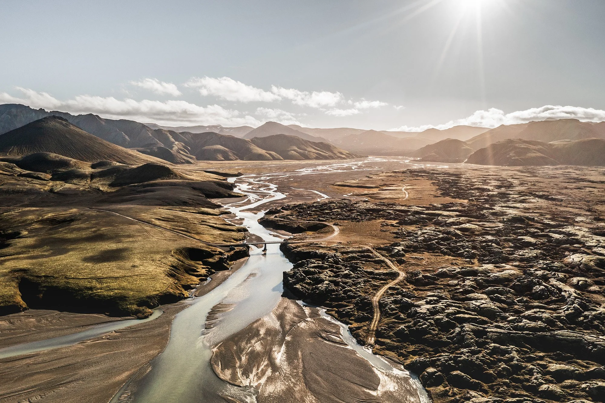Landschaft mit Fluss, Berge und Sonnenlicht im Himmel