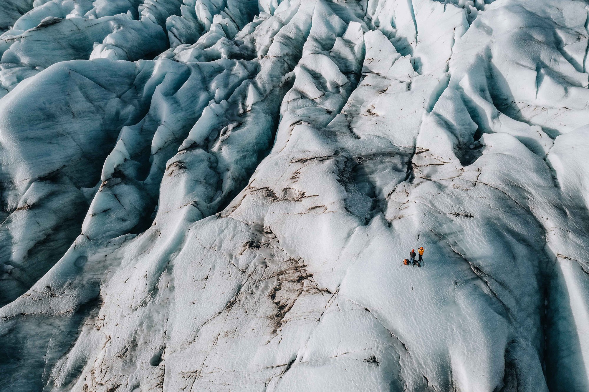 Zwei Bergsteiger auf einem Gletscher in eisiger Landschaft mit großen Eisklippen
