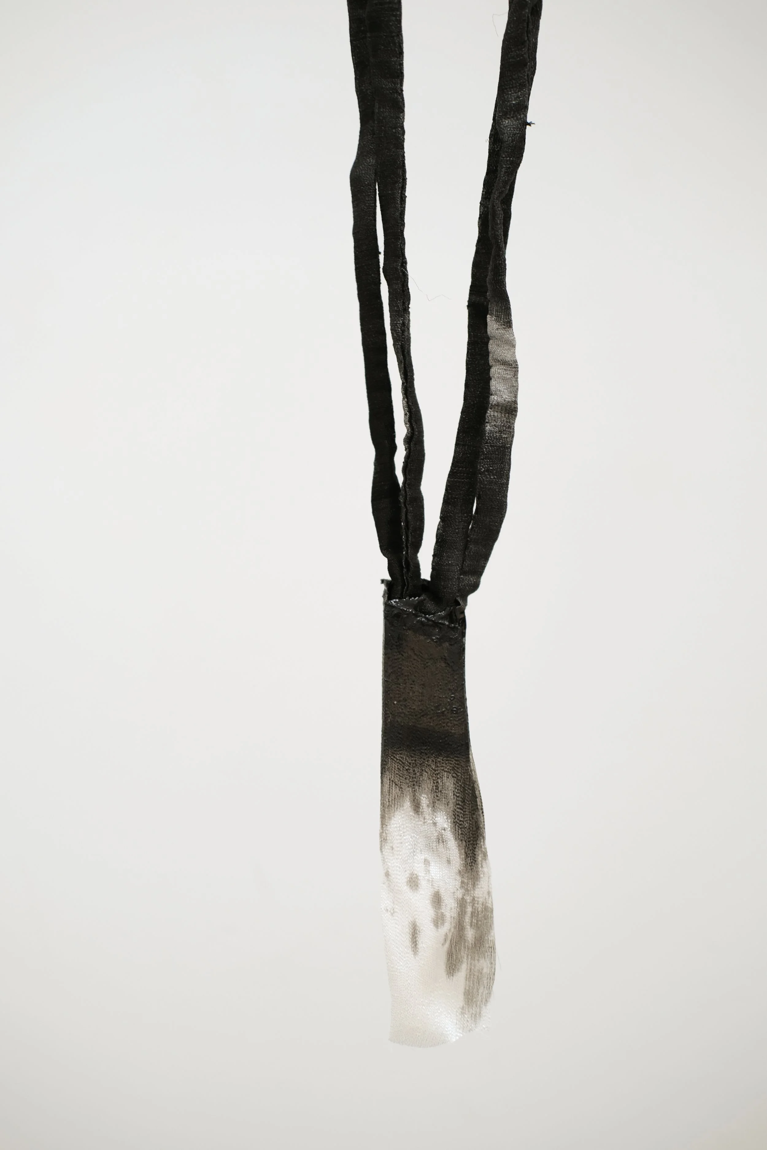 Une sculpture ou une œuvre d'art abstraite suspendue, en noir, blanc et nuances de gris, avec un fond blanc.