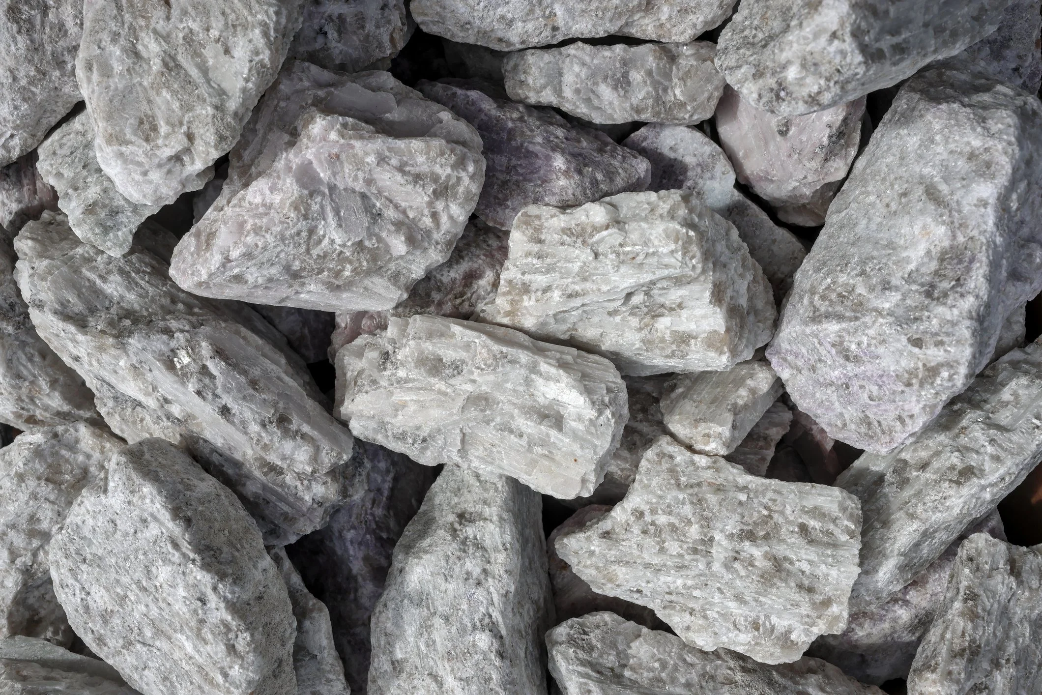 A close-up view of a pile of grey and white rocks with rough surfaces.