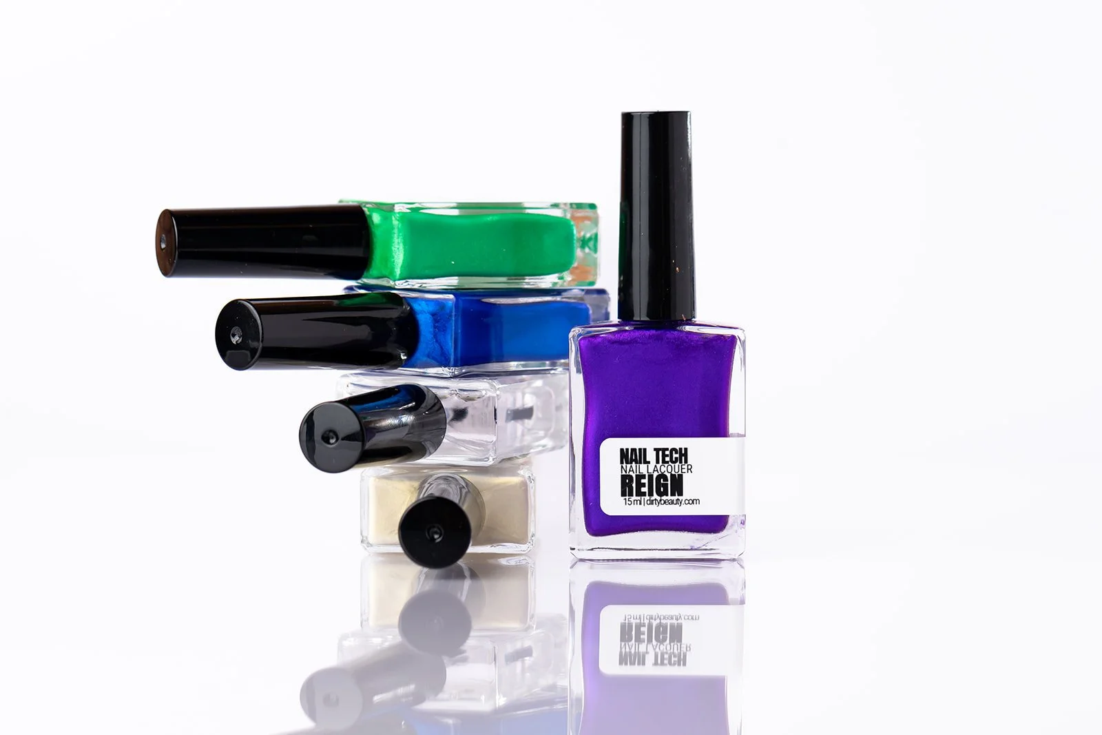 Stacked bottles of colorful nail polish on a reflective surface with a white background.