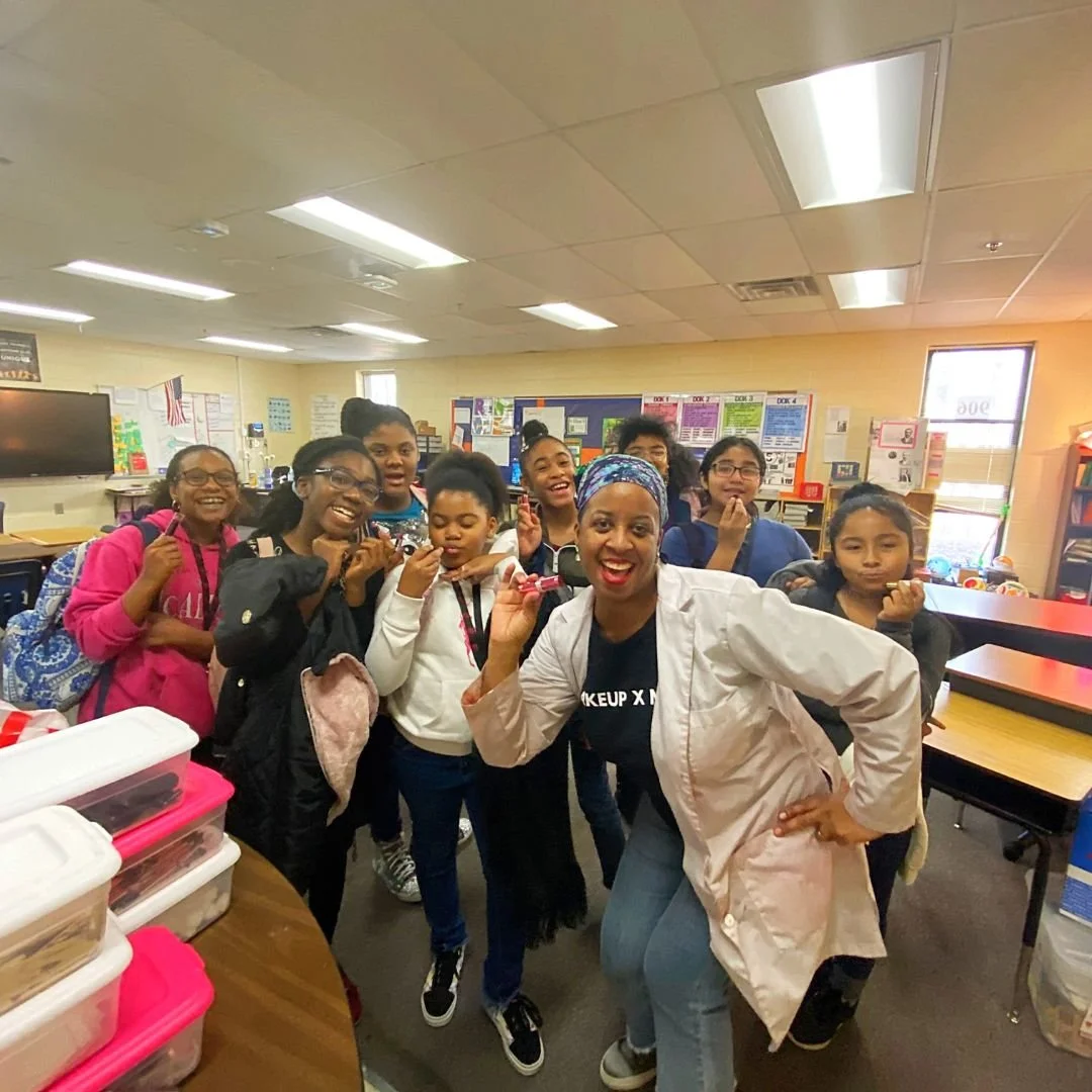 Group of young students and teacher smiling and posing for a photo in a classroom.