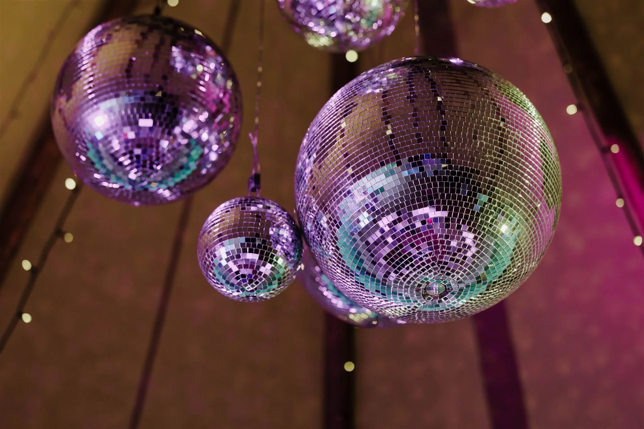 Multiple disco balls in various sizes hanging from the ceiling, reflecting colorful lights.
